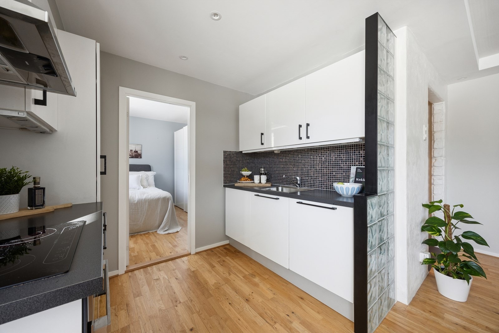 Fliser mellom benkeplate og overskap gir et stilrent uttrykk, og de integrerte hvitevarene bidrar til en helhetlig og funksjonell arbeidsflate. Galleribilde