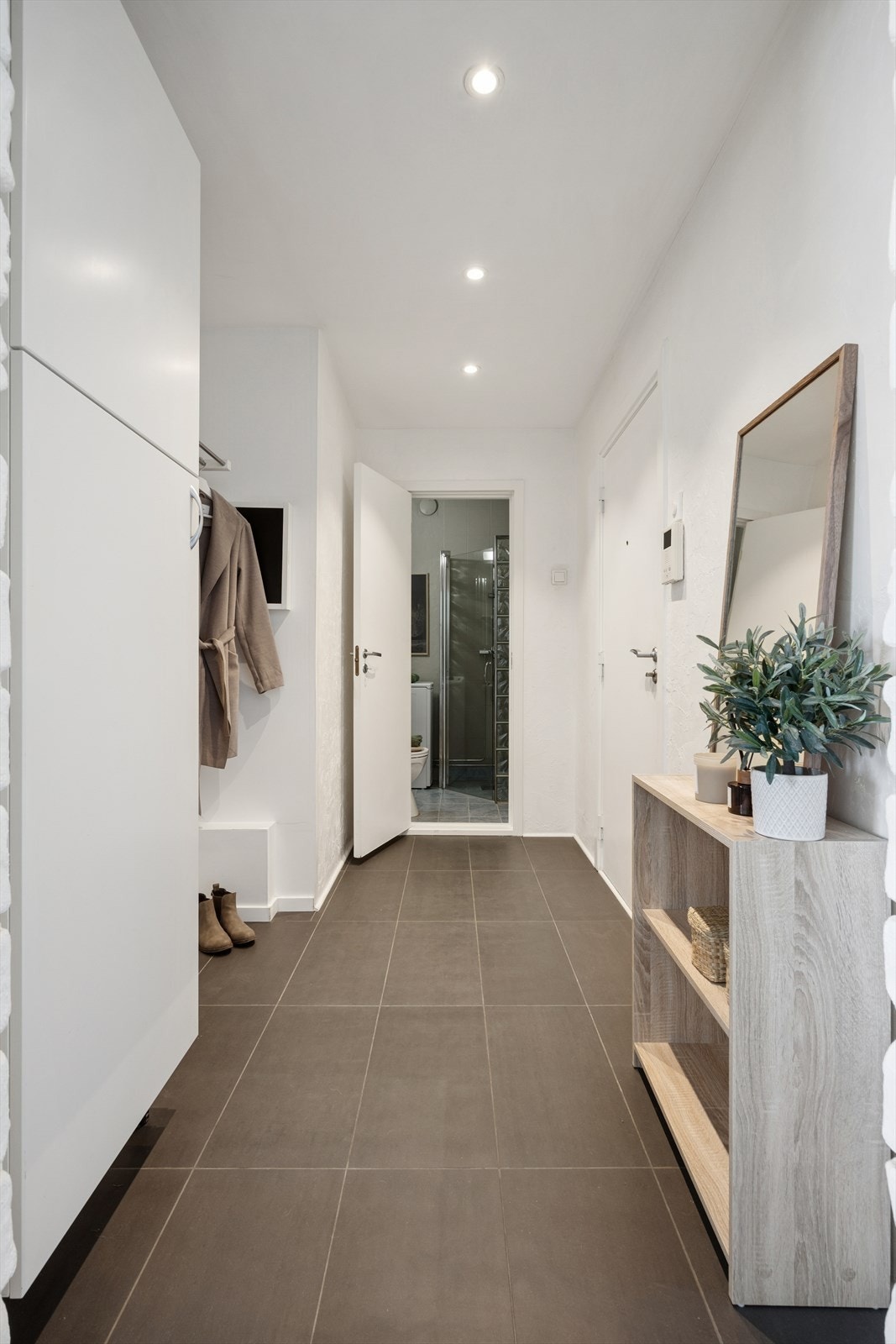 Entréen er lys og innbydende, med en praktisk garderobenisje rett innenfor døren som gir gode oppbevaringsmuligheter for sko og yttertøy. Gulvvarme bidrar til ekstra komfort, og gjør det til et behagelig område å komme hjem til. Galleribilde