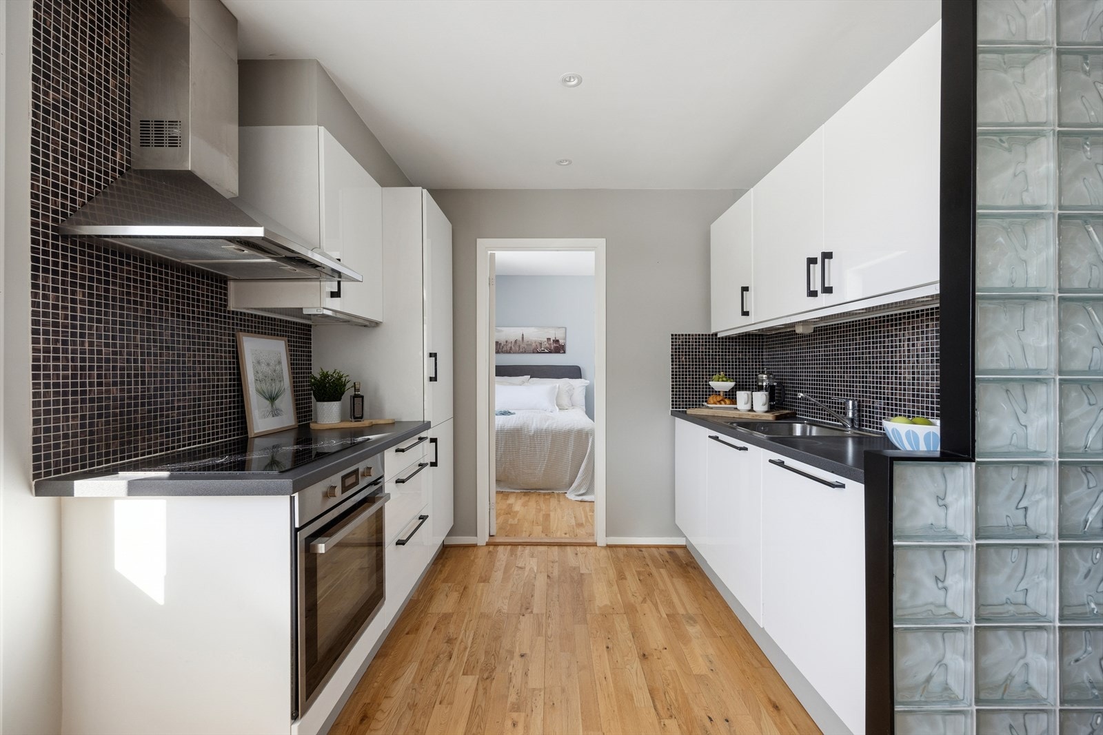 Kjøkkenet fremstår moderne med glatte, høyglans fronter og laminert benkeplate med nedfelt kum i rustfritt stål. Galleribilde