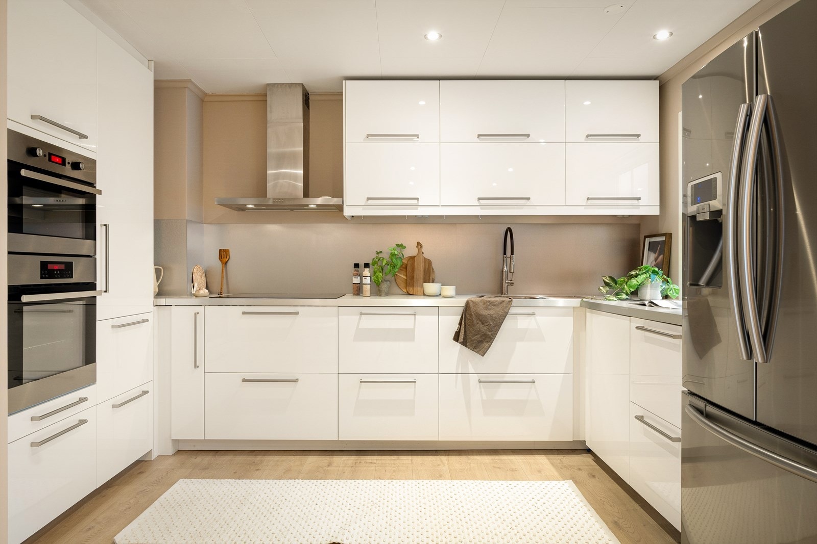 Kjøkkenet har høyglanspolerte hvite fronter og laminat benkeplate. Galleribilde