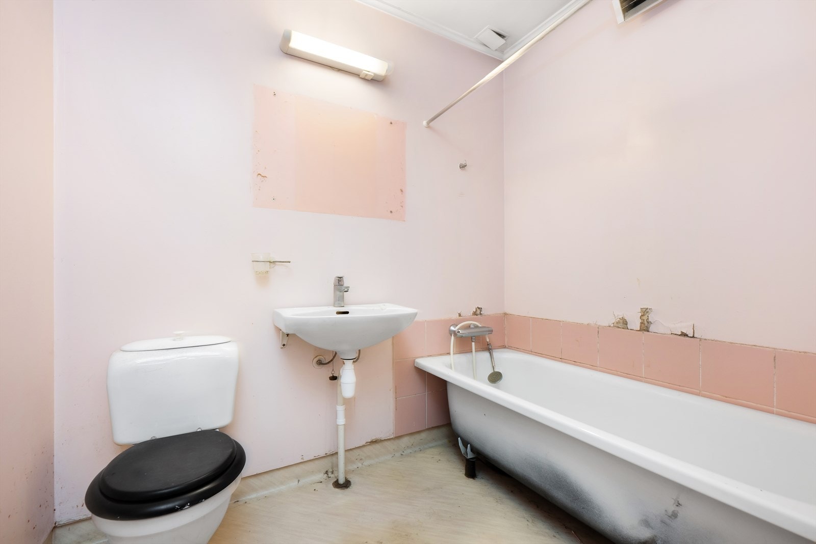 Badet er innredet med badekar, servant og toalett med behov for moderniseringer. Galleribilde