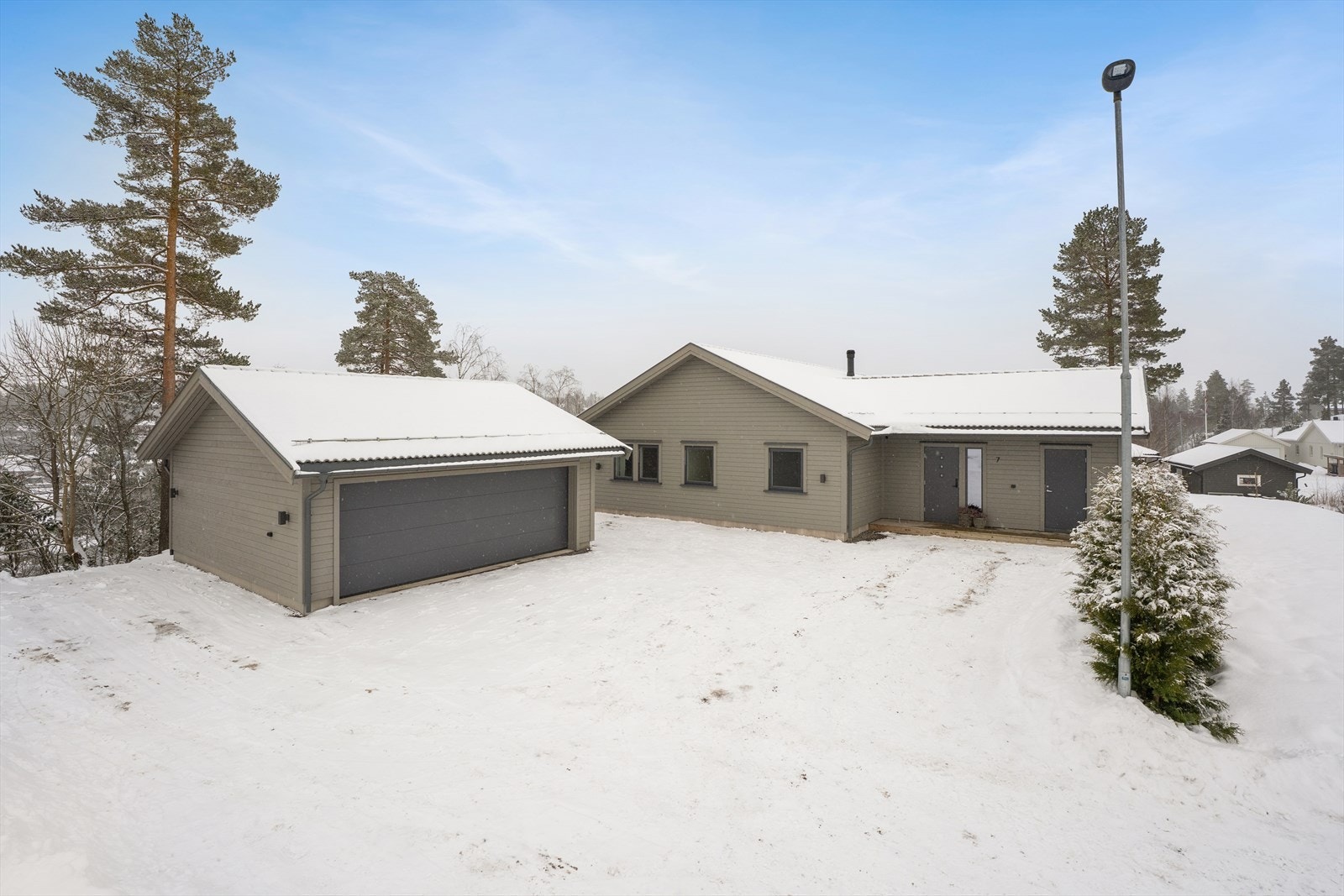 Det er gruset gårdsplass med plass til flere biler. På garasjeveggen er det også montert en elbillader Galleribilde