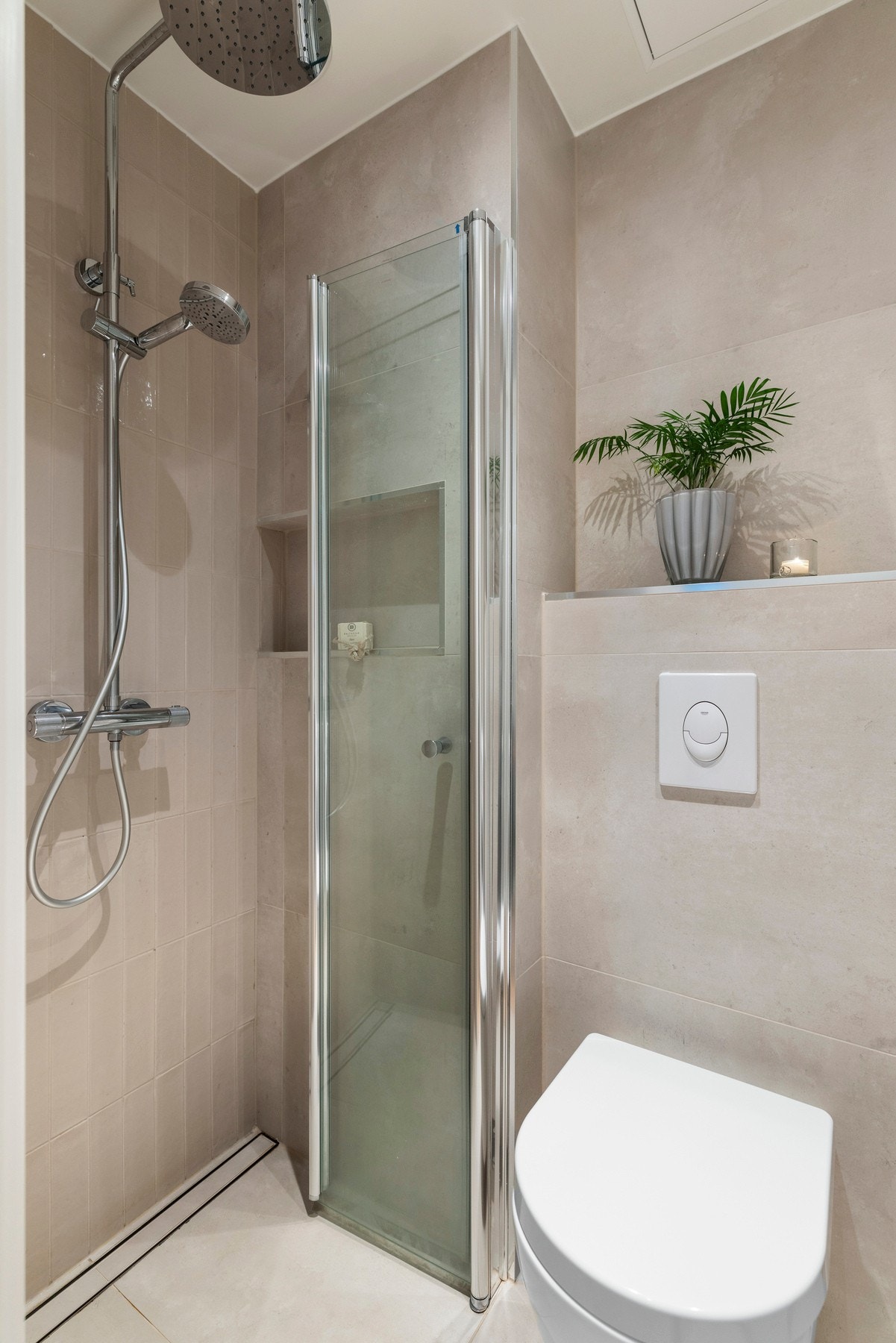 Badet har vegghengt toalett med innebygd sisterne kasse, servant på
vegghengt servantskap og vegghengte dusjdører i glass. Galleribilde