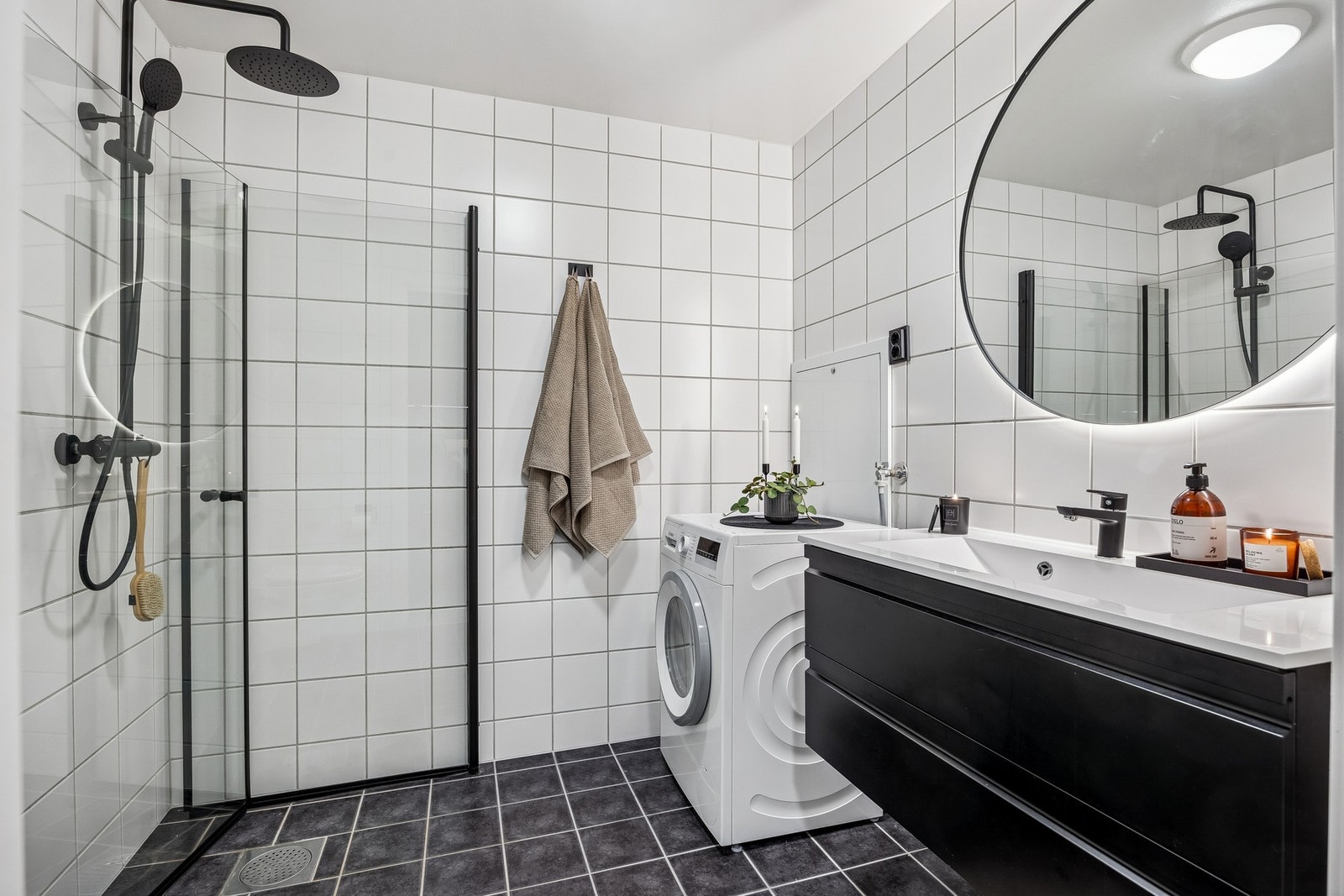 Pent flislagt baderom med moderne innredning og innfellbare dusjdører i glass. Galleribilde