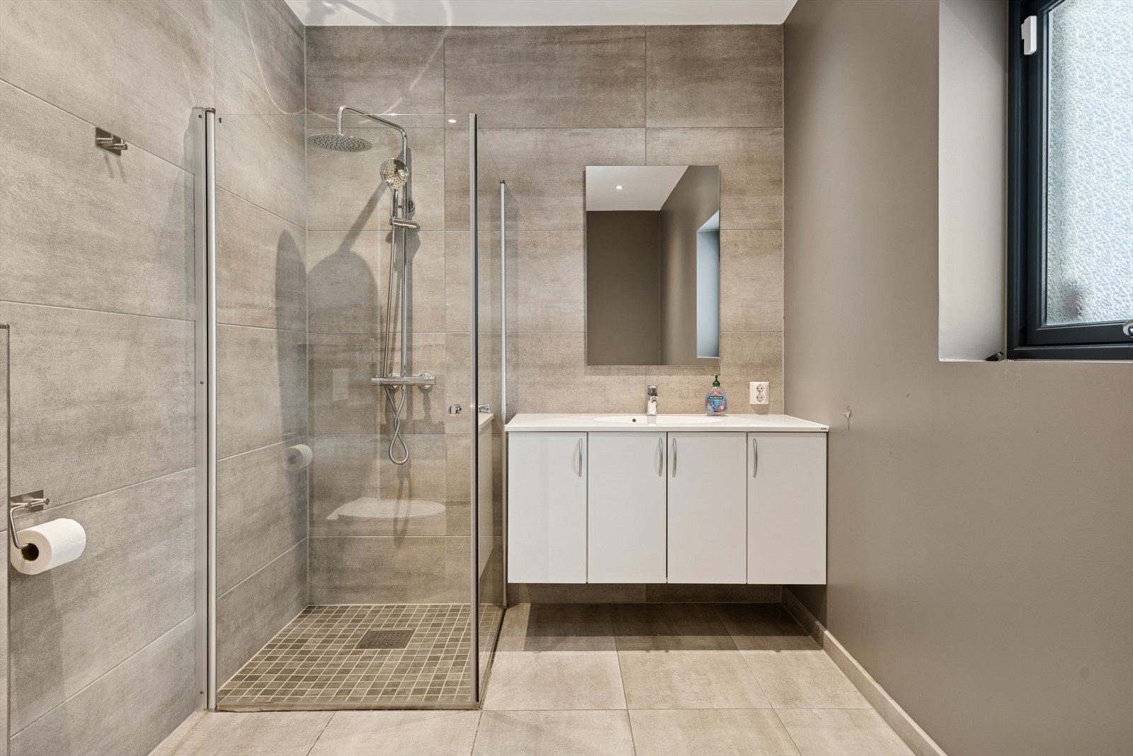 Badet har flislagt gulv med varmekabler, innredning med servant og vegghengt toalett. Galleribilde