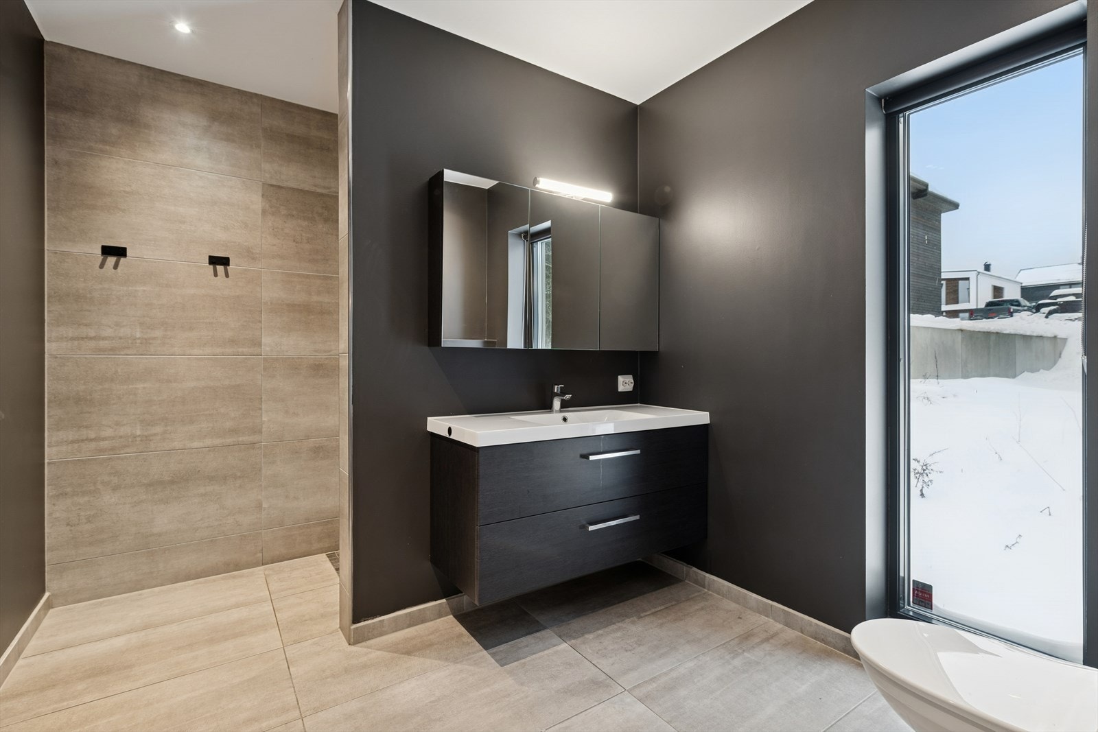 Badet tilknyttet hovedsoverommet har flislagt gulv med varmekabler og dusjnisje. Galleribilde