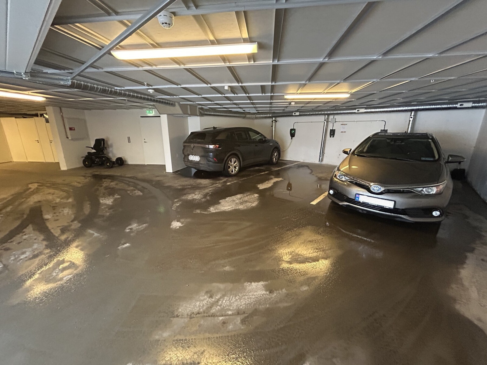 Garasje i kjelleren. Det er den ledige plassen i midten som følger med leiligheten. Denne har enkelt tilkomst og det er lett å navigere bilden i garasjen. Opplegg for Elbillading er utført, så her trenger man kun ladeboksen. Galleribilde