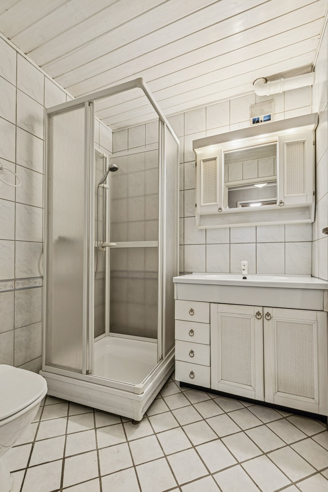 Flislagt bad med bl.a. gulvvarme, dusjkabinett, klosett, hel nedfelt servant og baderomsinnredning med servantskap, speilskap og lys over speilet. Galleribilde