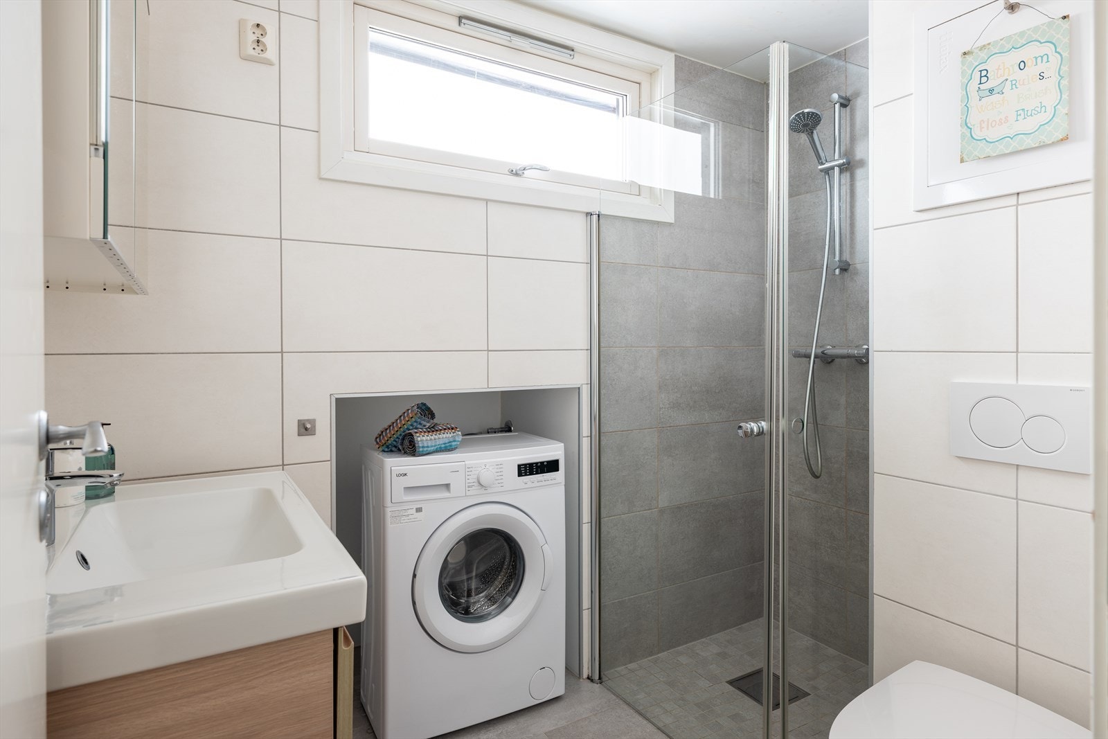 Pent, flislagt baderom med dusjhjørne, toalett, servant med underskap, speilskap og kran og avløp for vaskemaskin. Det er også varmekabler i gulv. Galleribilde