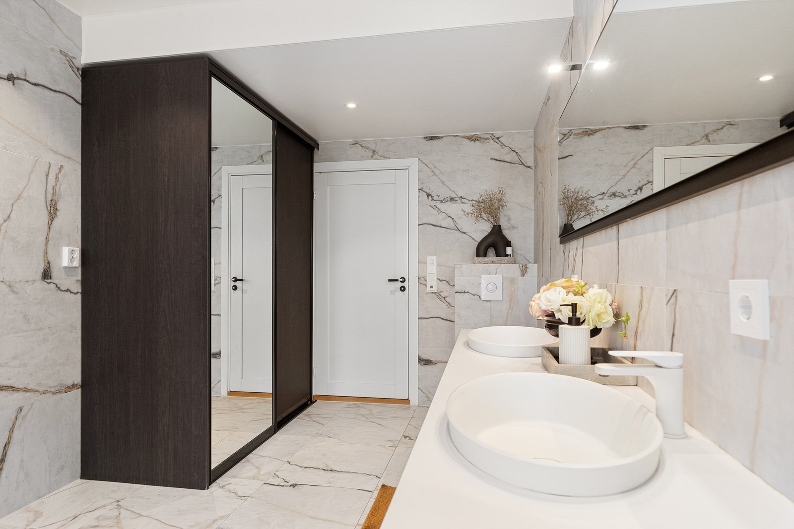 Badet har lekker innredning med dobbel servant, speil med lys, badekar, regndusj og toalett Galleribilde