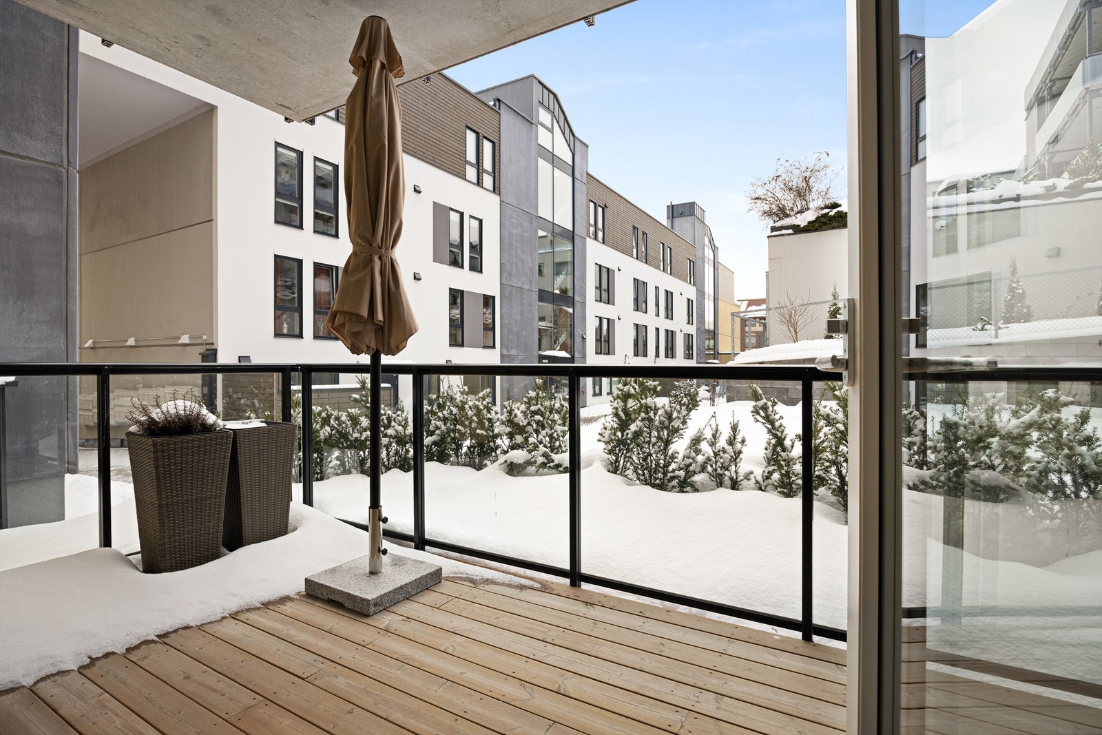 Terrasse med utvendig belysning, strømuttak, terrassebord på gulv og glassrekkverk. Galleribilde