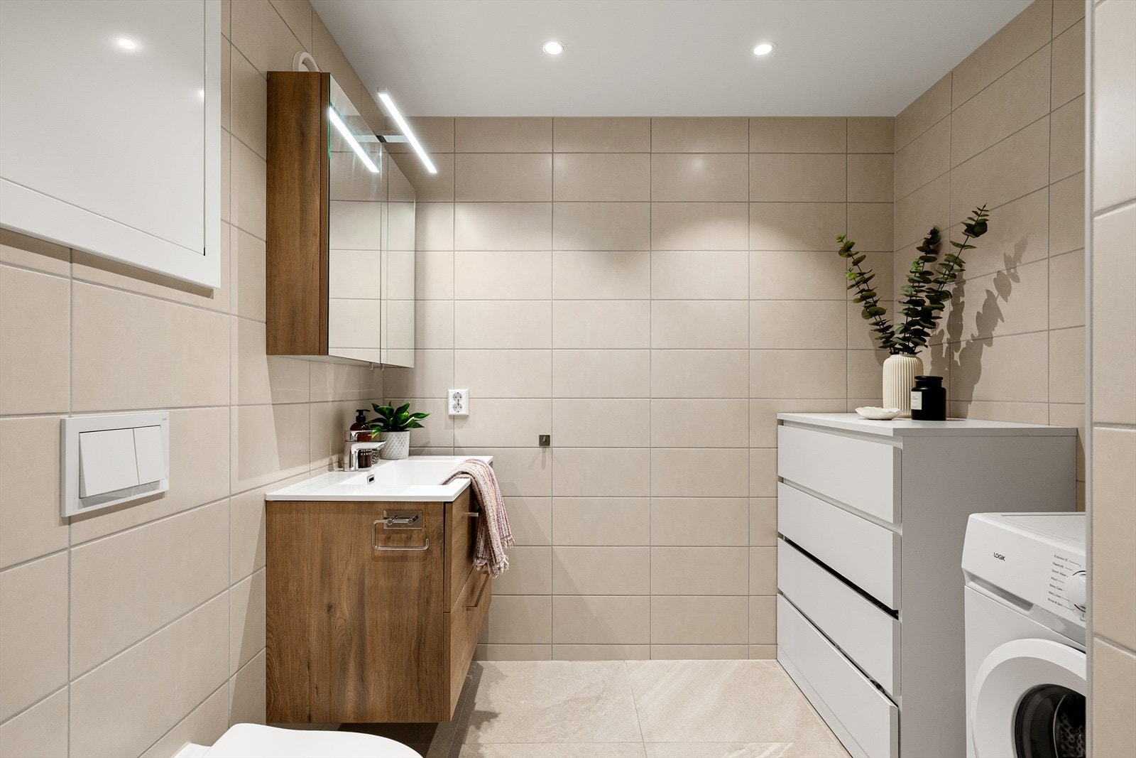 Badet har en moderne utførelse, flislagt med varmekabler i gulv og downlights i tak Galleribilde