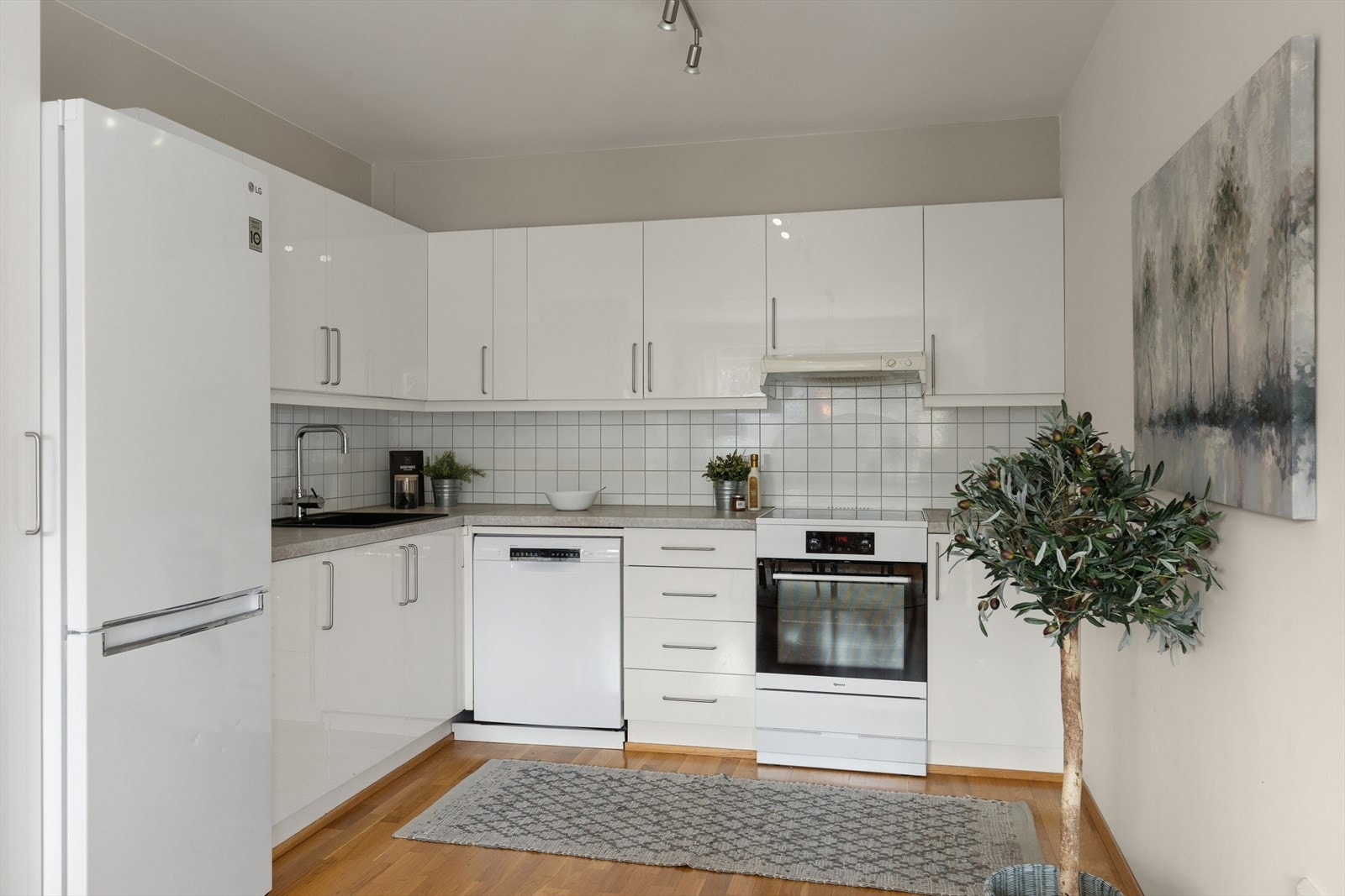 Innredningen har moderne glatte fronter, stål håndtak og en benkeplate i laminat som gir et moderne uttrykk Galleribilde