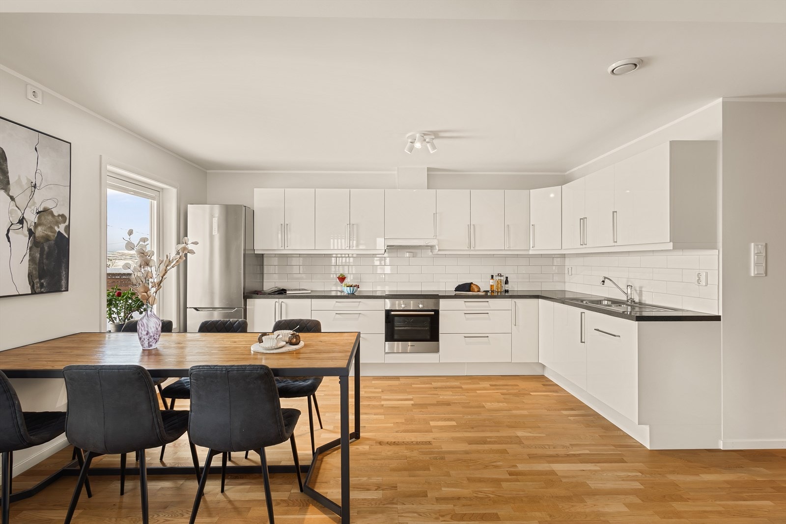 Pent kjøkken med innredning med slette fronter. Kjøkkenet har laminert benkeplate med nedfelt stålvask, ventilator og opplegg for oppvaskmaskin. Galleribilde