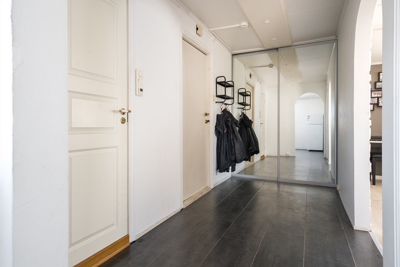 Når du kommer inn i leiligheten blir du møtt av en romslig entré med spotter i taket. Det er stor skyvedørsgarderobe med speilfronter. Galleribilde