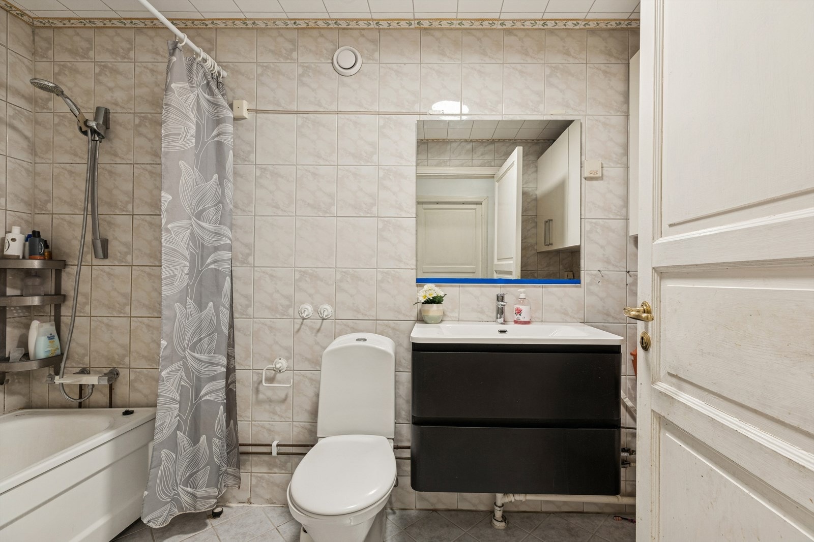 Eldre, flislagt bad utstyrt med servantinnredning, toalett og badekar. Galleribilde