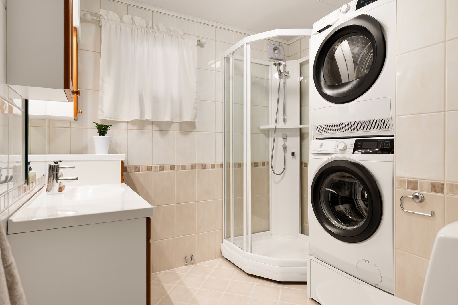 Flislagt bad med servant, toalett, dusjkabinett og opplegg for vaskemaskin. Det er varmekabler i gulvet. Galleribilde