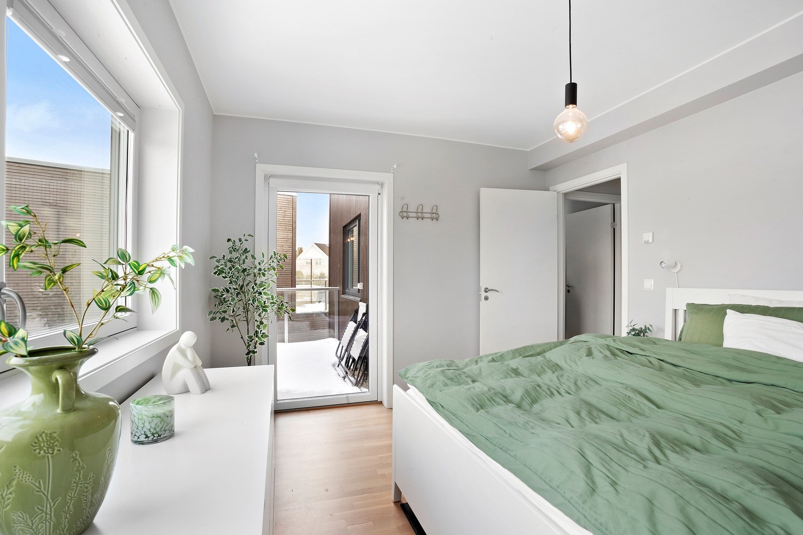 Soverom med utgang til balkong, lyse vegger og stort vindu som gir naturlig lysinnslipp. Galleribilde