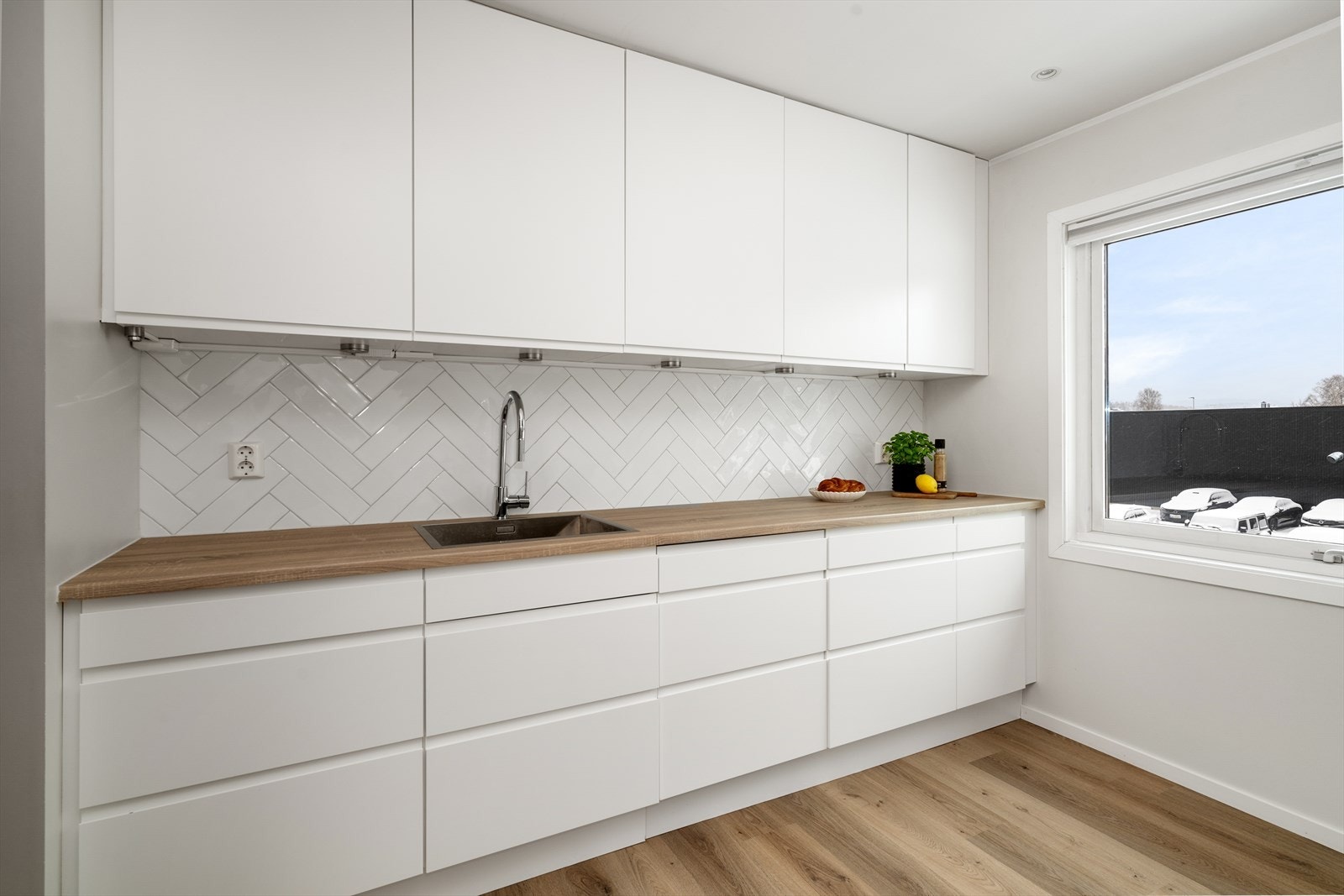 Det er gode arbeidsflater på laminerte benkeplater, og flis mellom over- og underskap som beskytter veggen mot vannsprut. Kjøkkenet har innredning på to sider for god oppbevaringsplass, i tillegg til åpen veggplass for et lett og avslappet uttrykk. Galleribilde