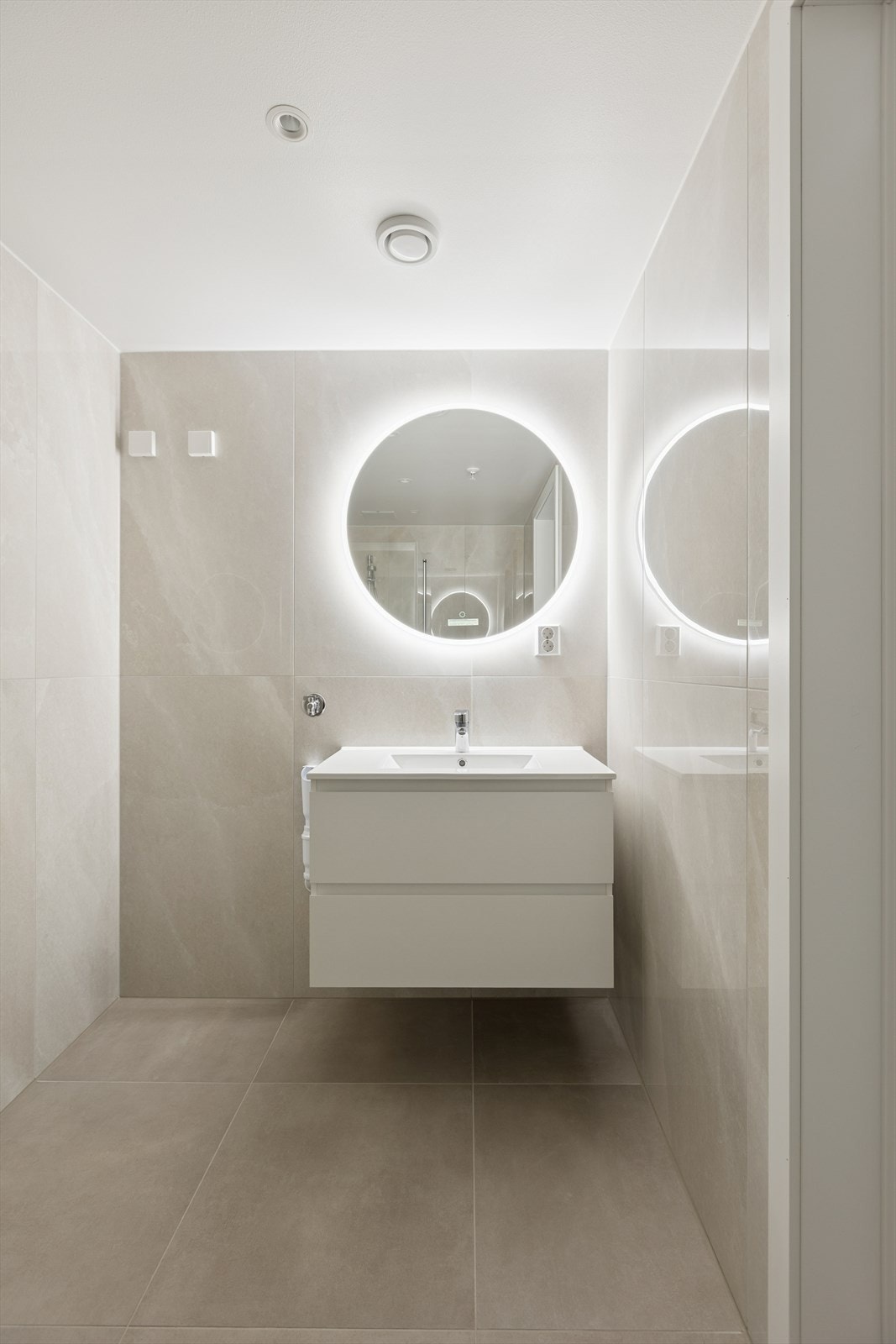 Flott flislagt bad med bl.a. gulvvarme, servantskap med glatte, folierte fronter og heldekkende servant, speil med belysning på vegg over servant og opplegg for vaskemaskin/tørketrommel. Galleribilde