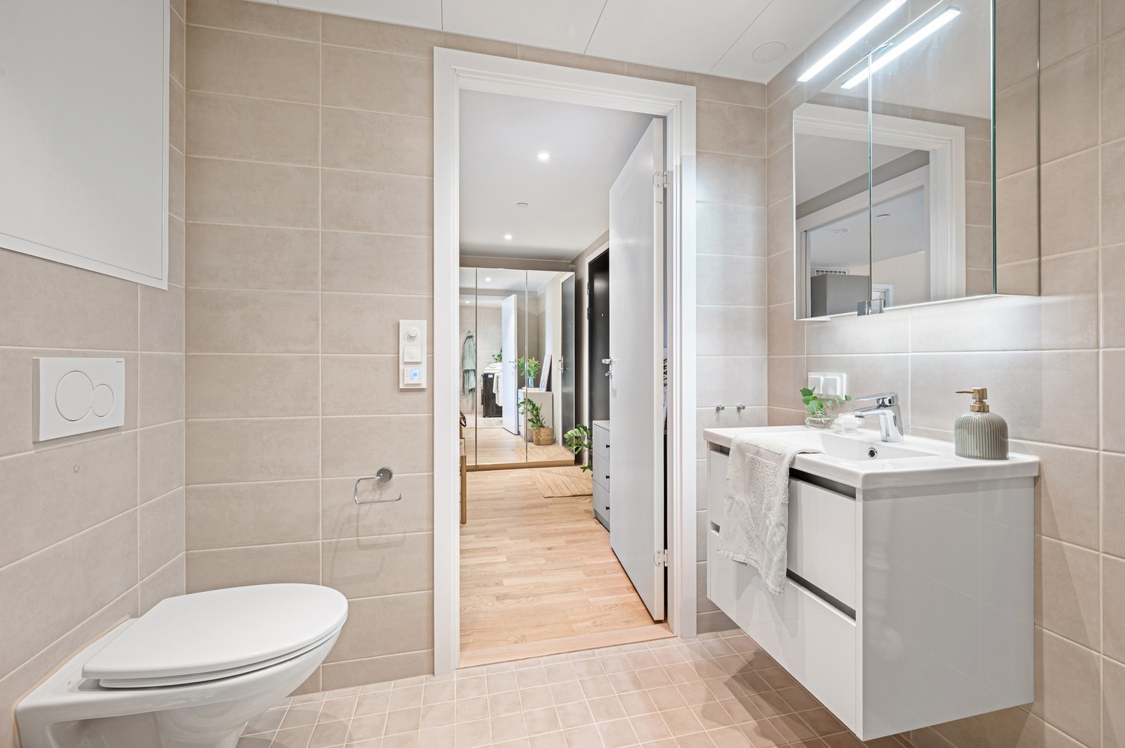 Baderommet er innredet med dusjhjørne, veggmonert WC, servant på underskap og speil. Galleribilde