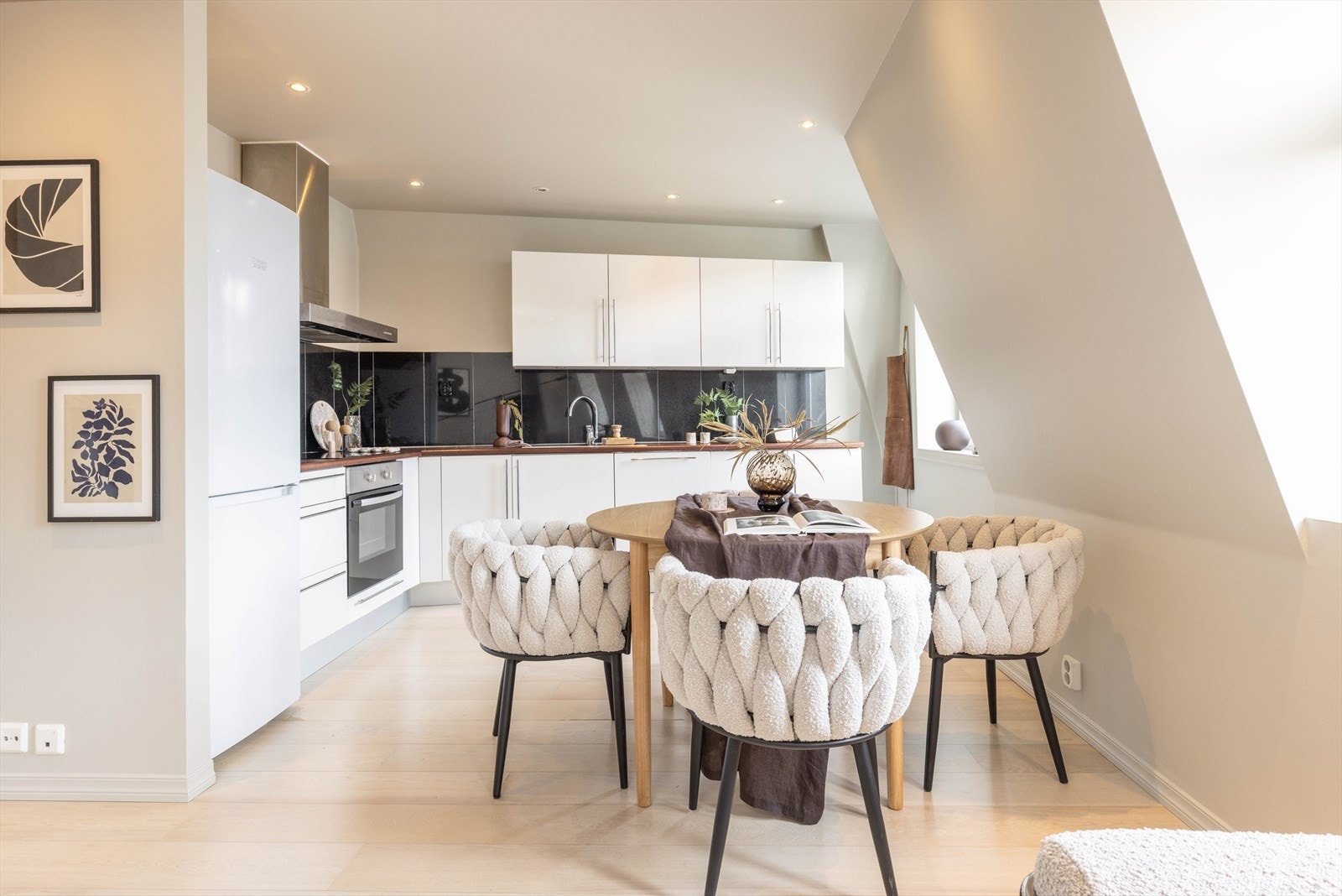 Den åpne løsningen fungerer utmerket. Kjøkkeninnredningen ligger i en egen sone. WFM-kjøkkenet strekker seg langs veggen i en praktisk L-form og har en pen og tidløs fremtoning med hvite, glatte fronter og benkeplate i tre. Galleribilde