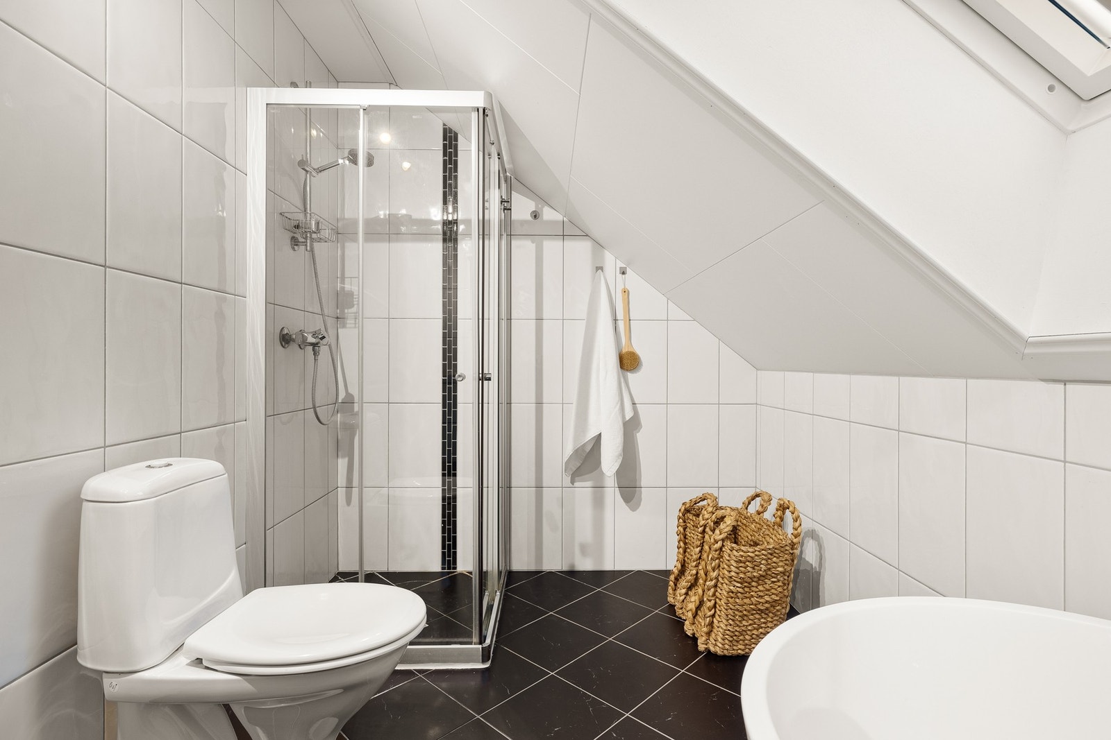 Det er utstyrt med toalett, dusjhjørne, badekar og baderomsinnredning med speil og belysning. Galleribilde