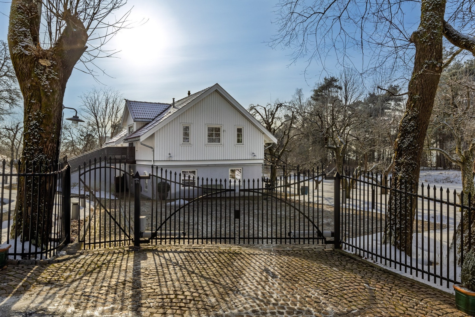 Elegant opparbeidet gårdsplass med bl.a. elektrisk smijernsport og gårdsplass belagt med brostein i rød granitt Galleribilde