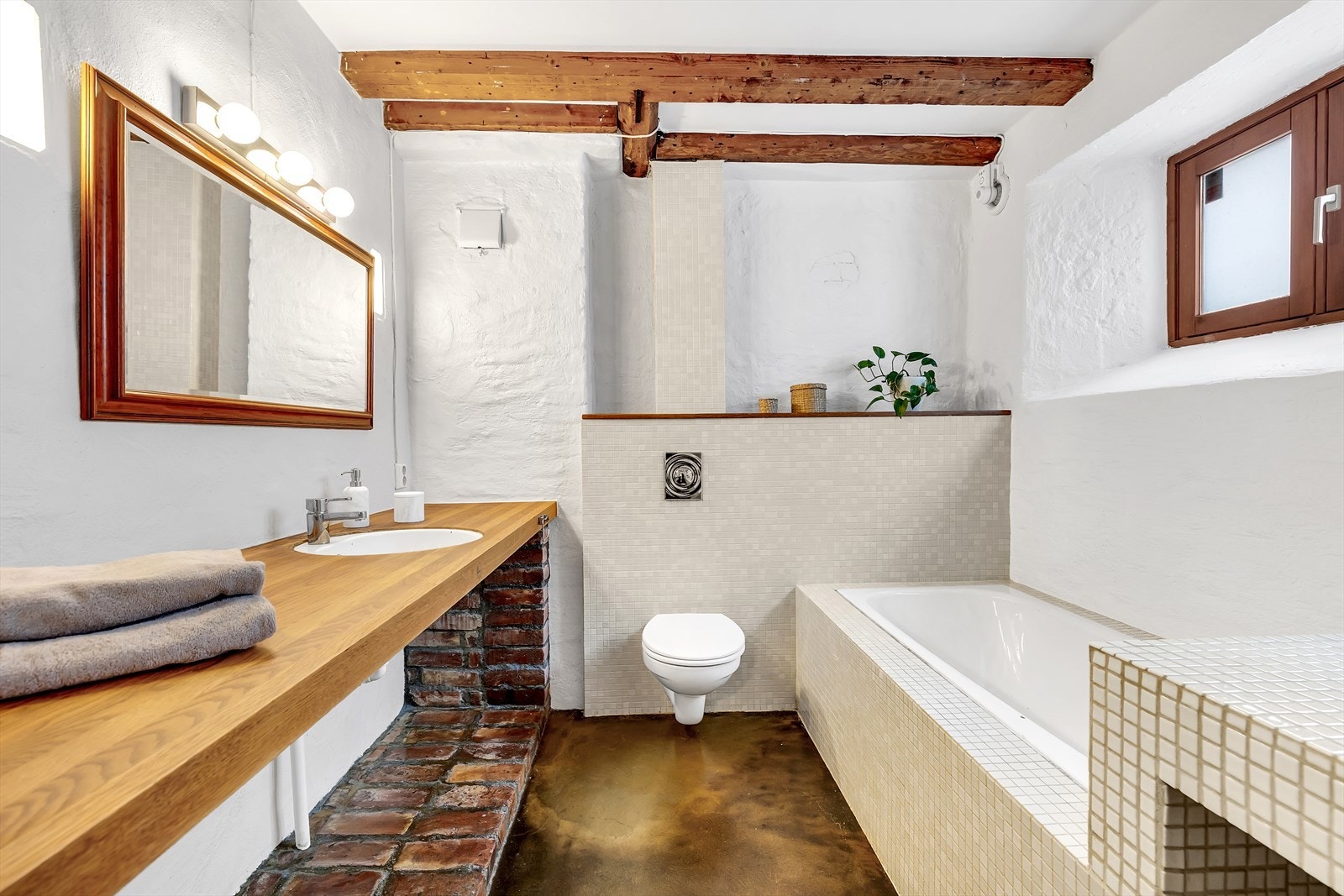 Romslig baderom fra 2003. Her er det epoxygulv med underliggende gulvvarme, vegger med malt mur og fliser samt tak med malte plater og innfelte bjelker. Galleribilde