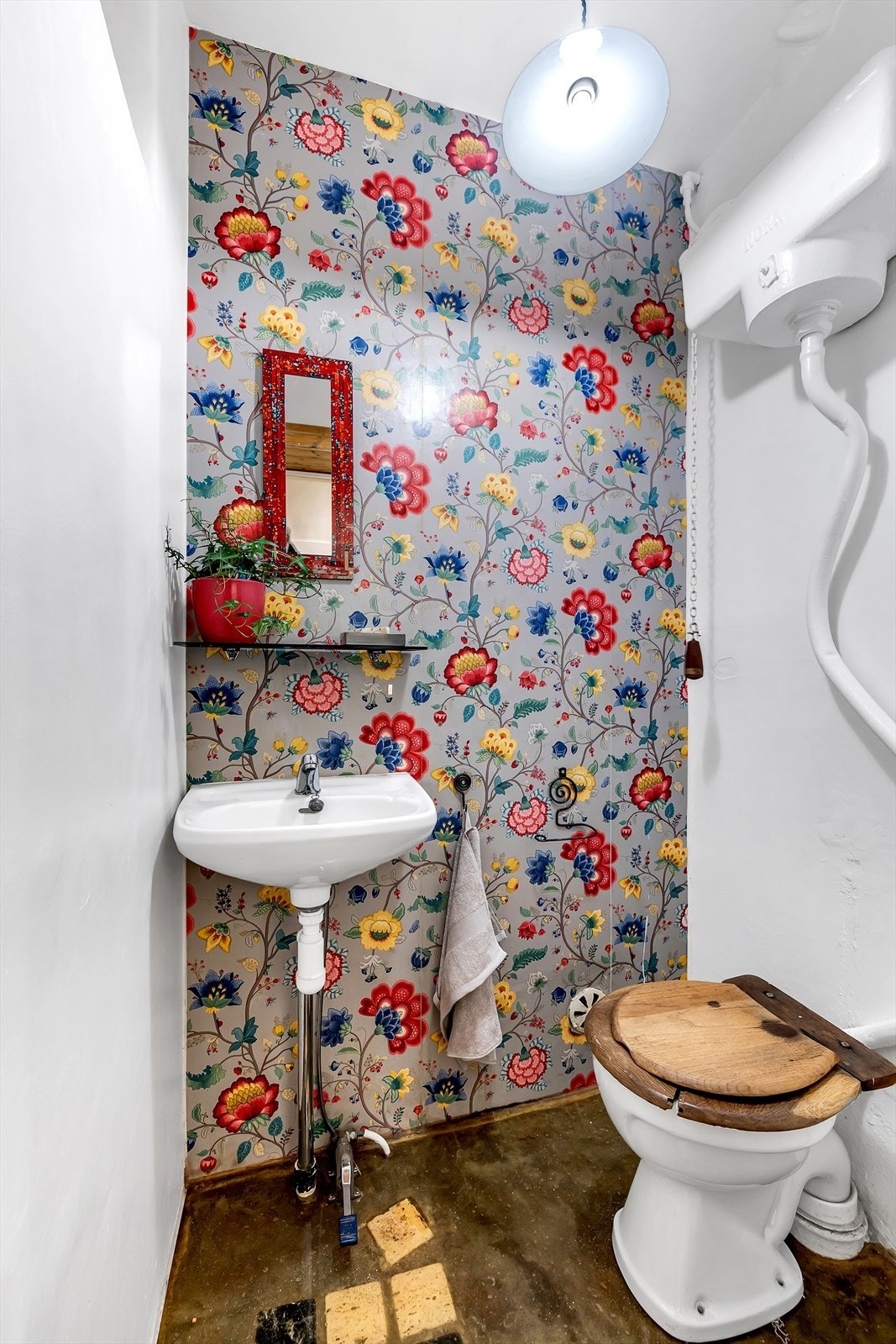 Toalettrommet har tapetsert vegg og epoxy på gulvet. Innredet med servant og wc. Galleribilde