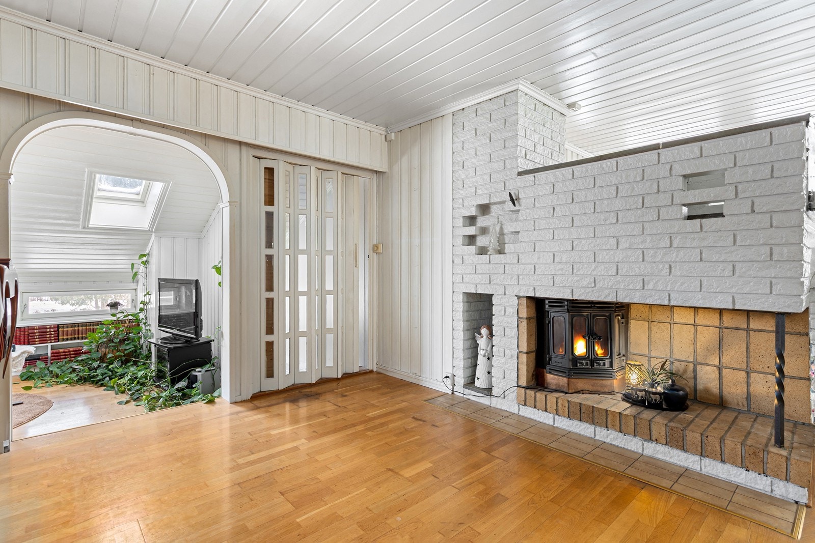 I stuen har man en naturlig romdeler med innmurt peisinnsats, og det er et par trappetrinn ned til en ekstra sone. Galleribilde