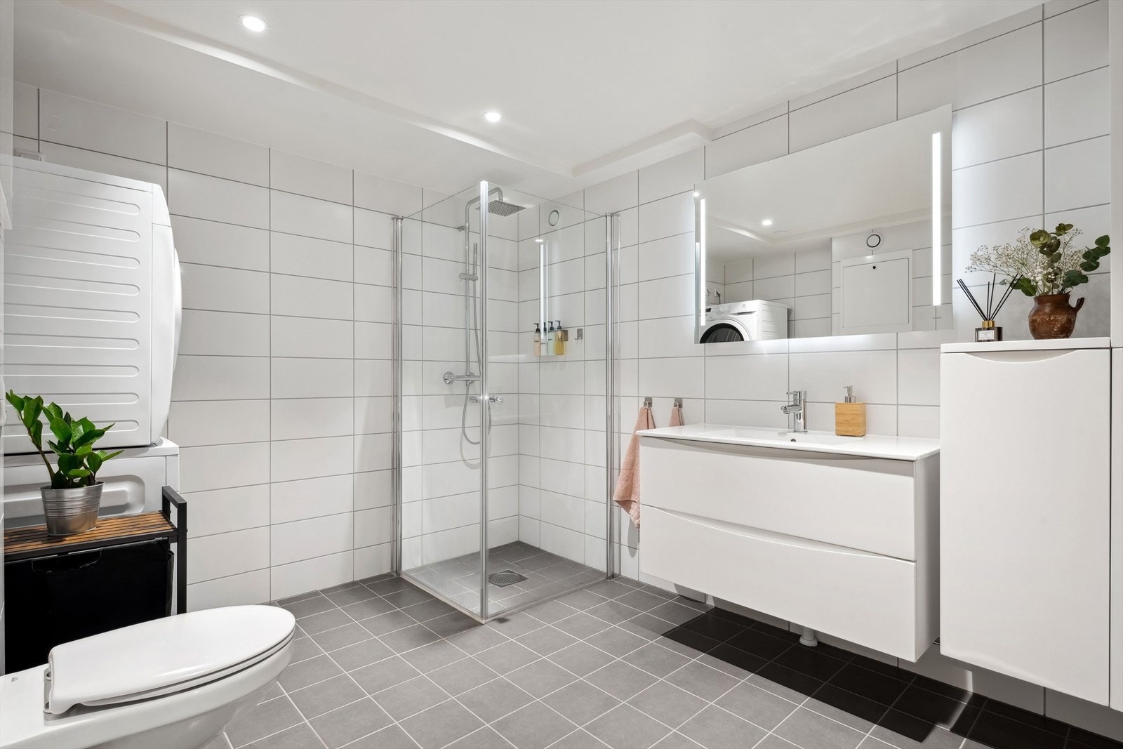 Dusjsonen har glassdører og regndusj, og rommet har en moderne servantinnredning med skuffer. Galleribilde