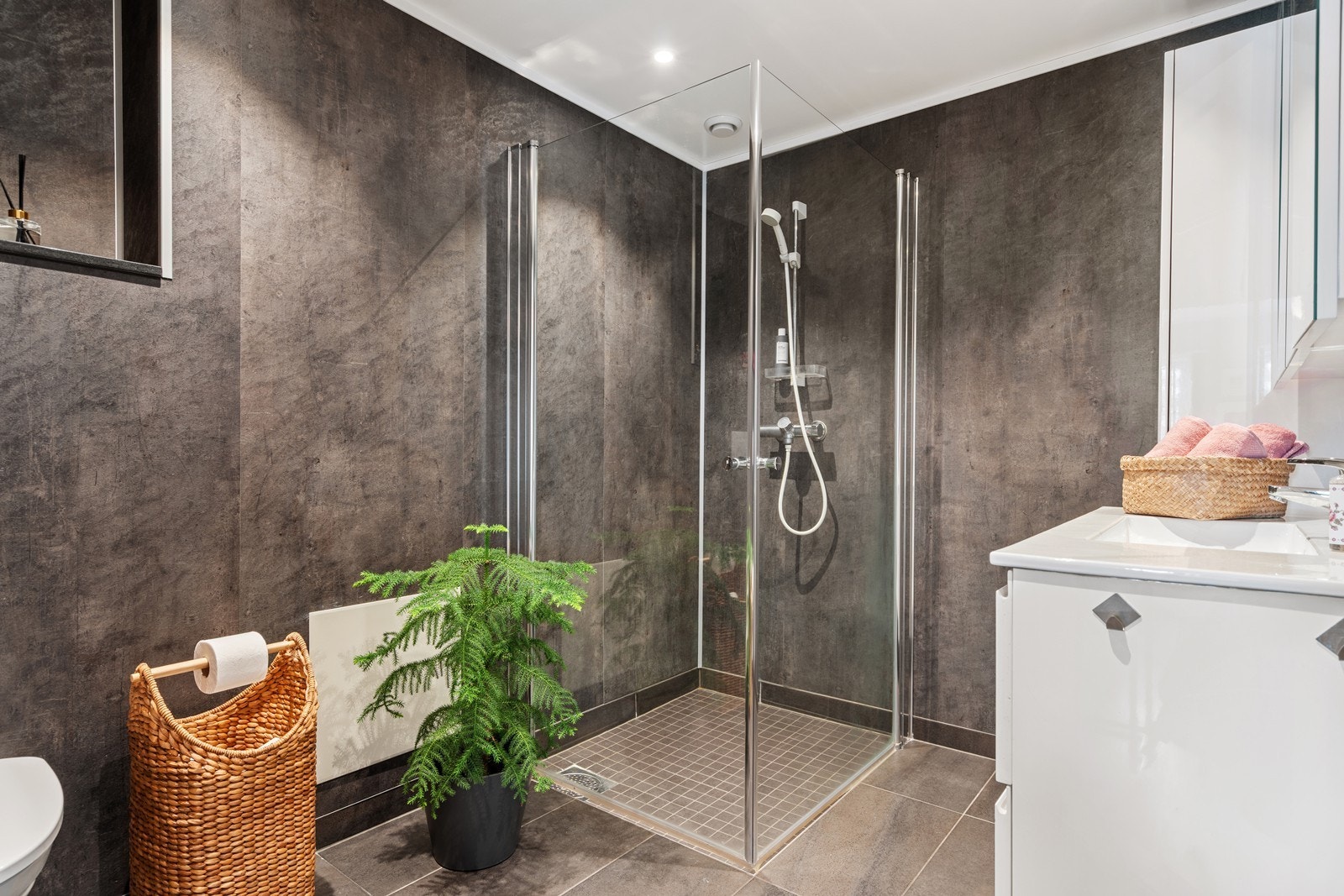 Tidsriktig og delikat baderom som er innredet med heldekkende servant, veggmontert toalett og dusjvegger/hjørne. Galleribilde