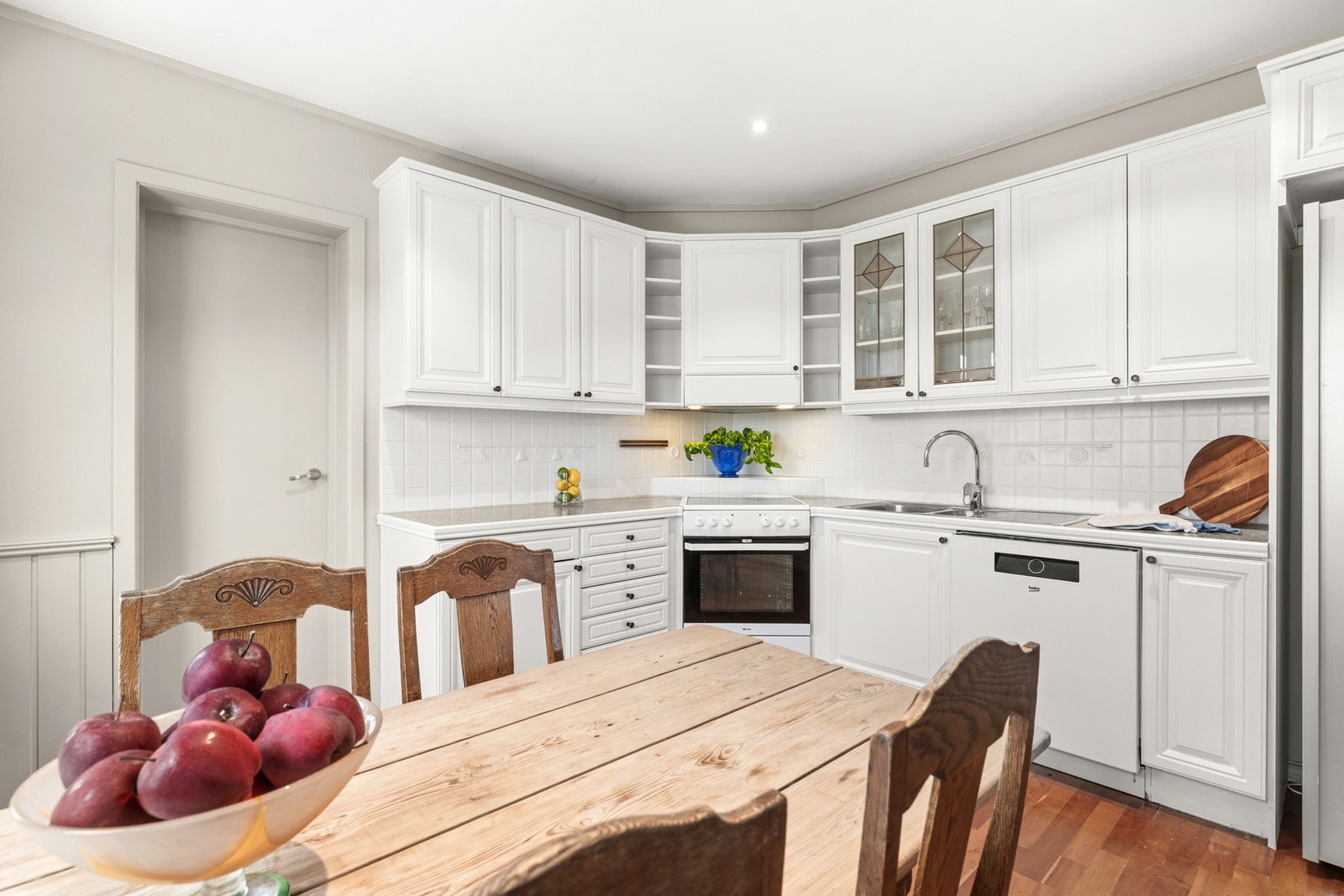 Kjøkken med profilerte hvite fronter, laminat benkeplate med nedfelt stålkum med to basseng og rillebrett, ettgreps kjøkkenkran. Galleribilde