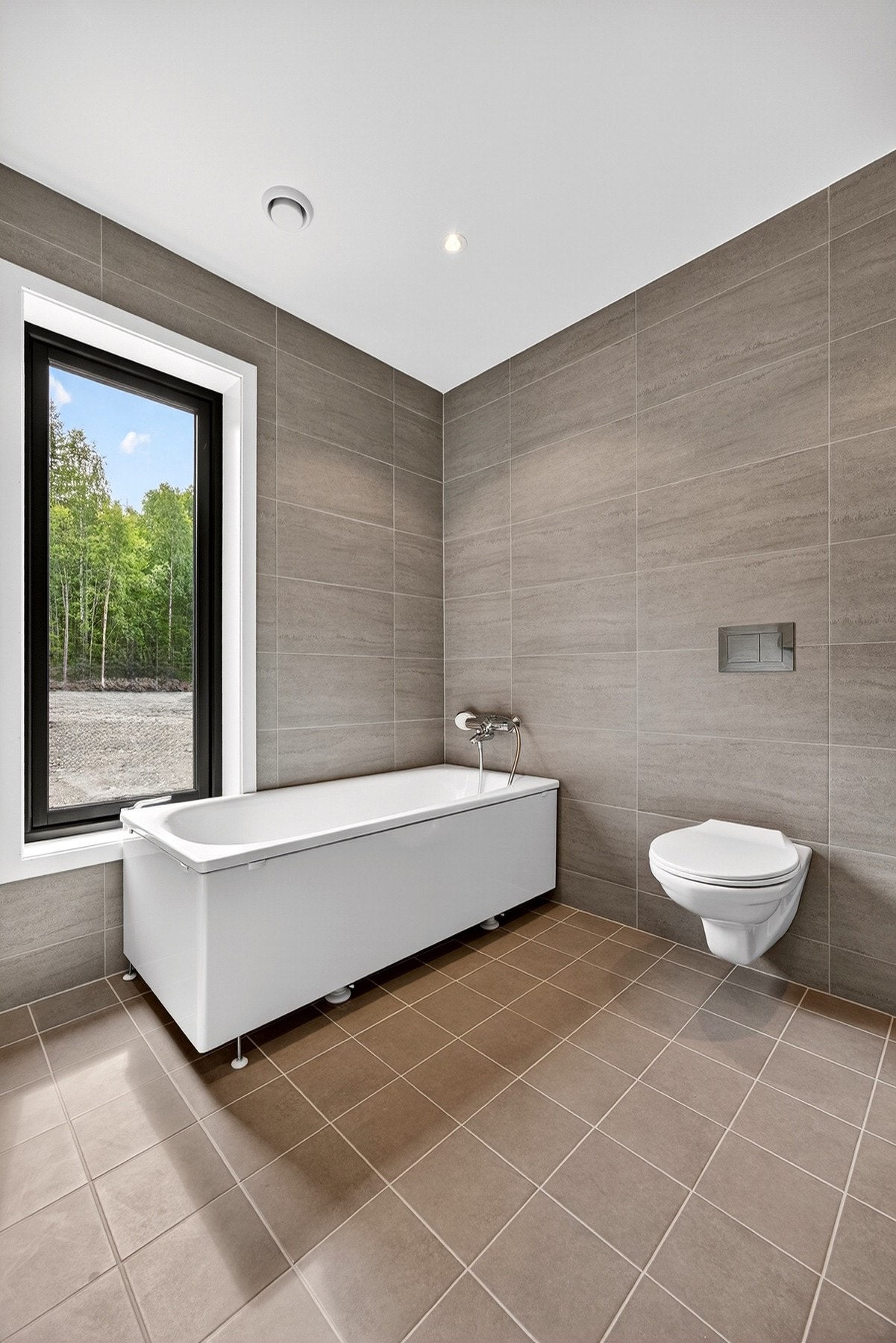 Badene får pene fliser fra Norfloor på gulv og vegger (medium grey). Badekar er ikke en del av standard leveransen. Bilder er ikke av selve boligen, kun ment som illustrasjon. Galleribilde