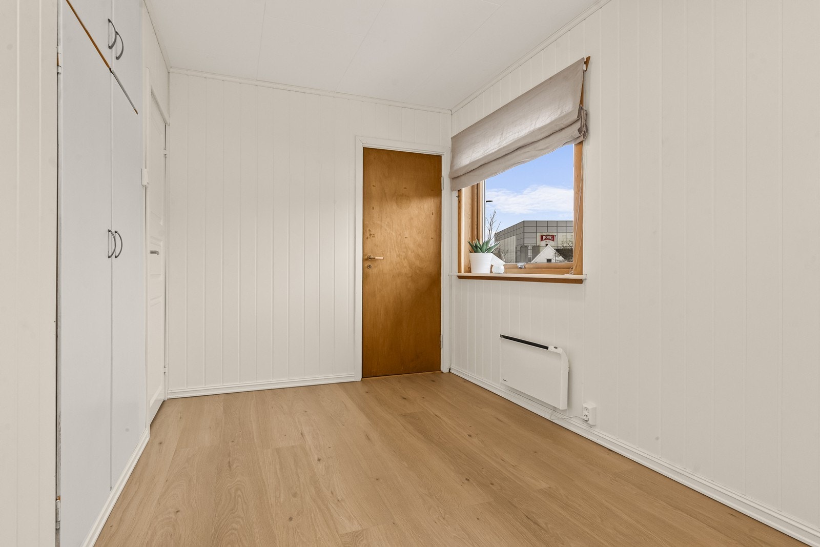 Det andre soverommet i etasjen har laminatgulv og vegger med MDF-panel. Her er det integrerte garderobeskap fra byggetiden. Galleribilde