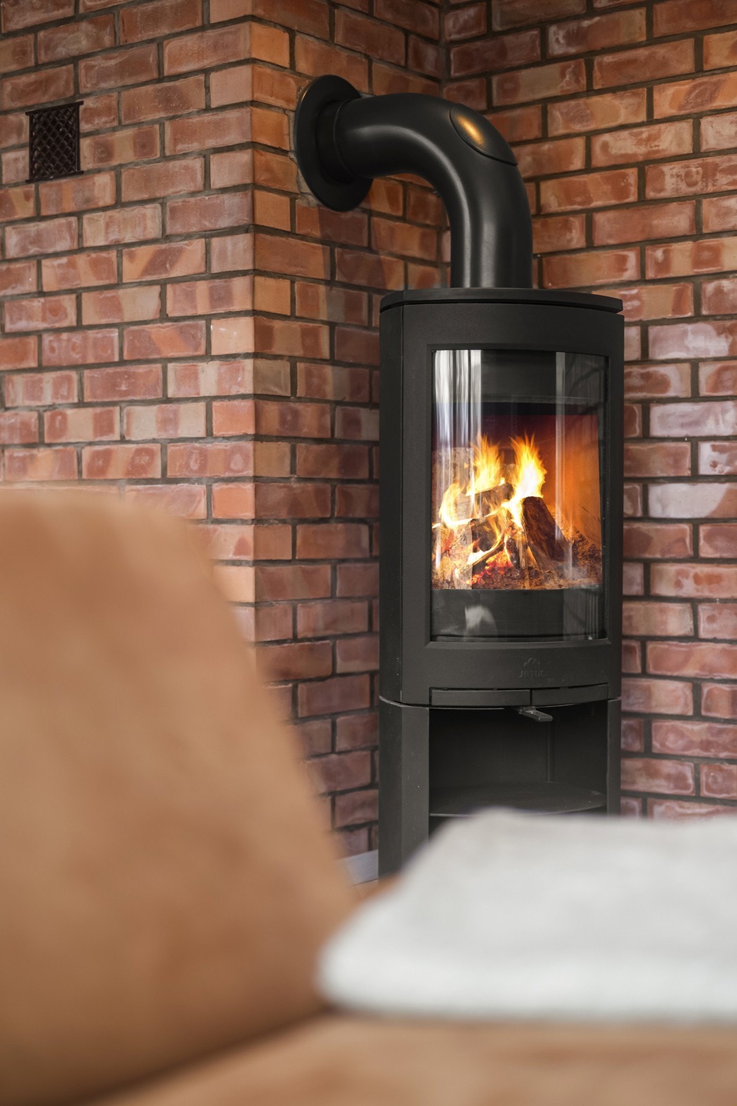 En vedovn fra 2020, plassert mot en mursteinspipe, gir både varme og lun atmosfære. Galleribilde