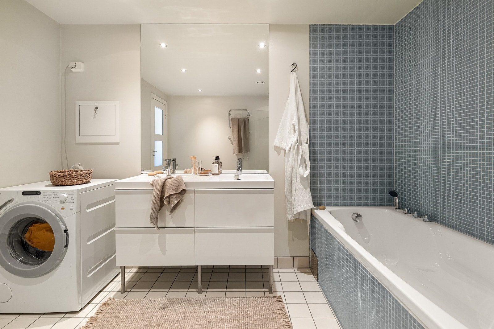 Videre er det dobbelt servantskap med glatte fronter, to heldekkende servanter, toalett, speil på vegg over servant, og vaskemaskin. Galleribilde