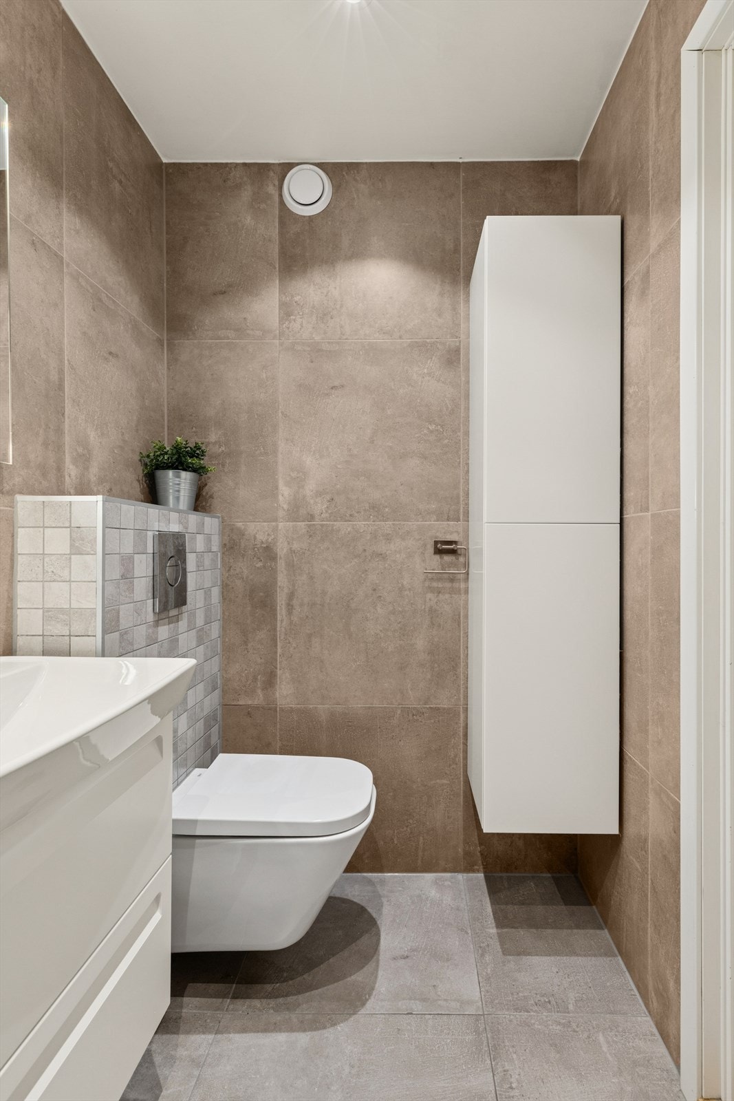 Rommet har servant, veggmontert toalett, dusjvegger/hjørne og opplegg for vaskemaskin. Galleribilde