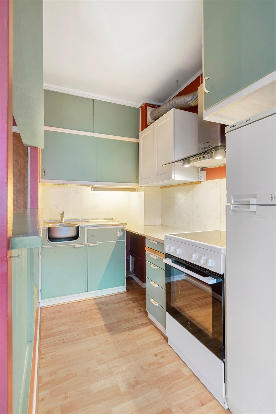 Kjøkkeninnredning av eldre, plassbygd type med frittstående komfyr og kjøleskap. Galleribilde