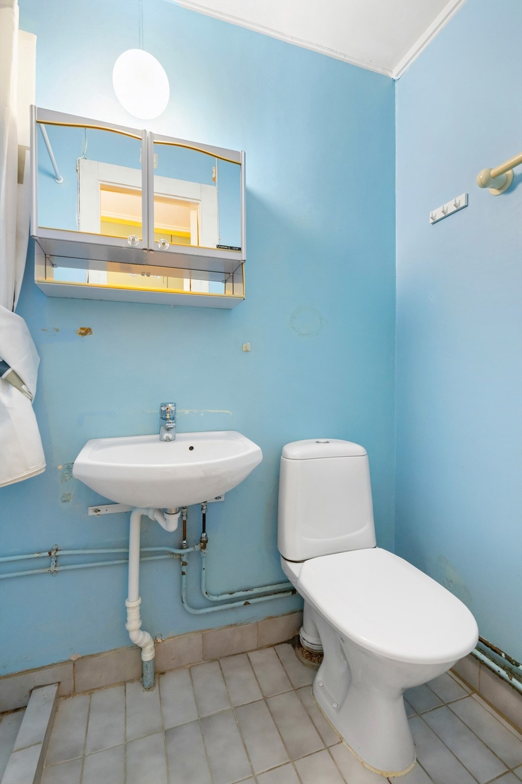 Badet er utstyrt med gulvmontert toalett, servant og speilskap. Galleribilde