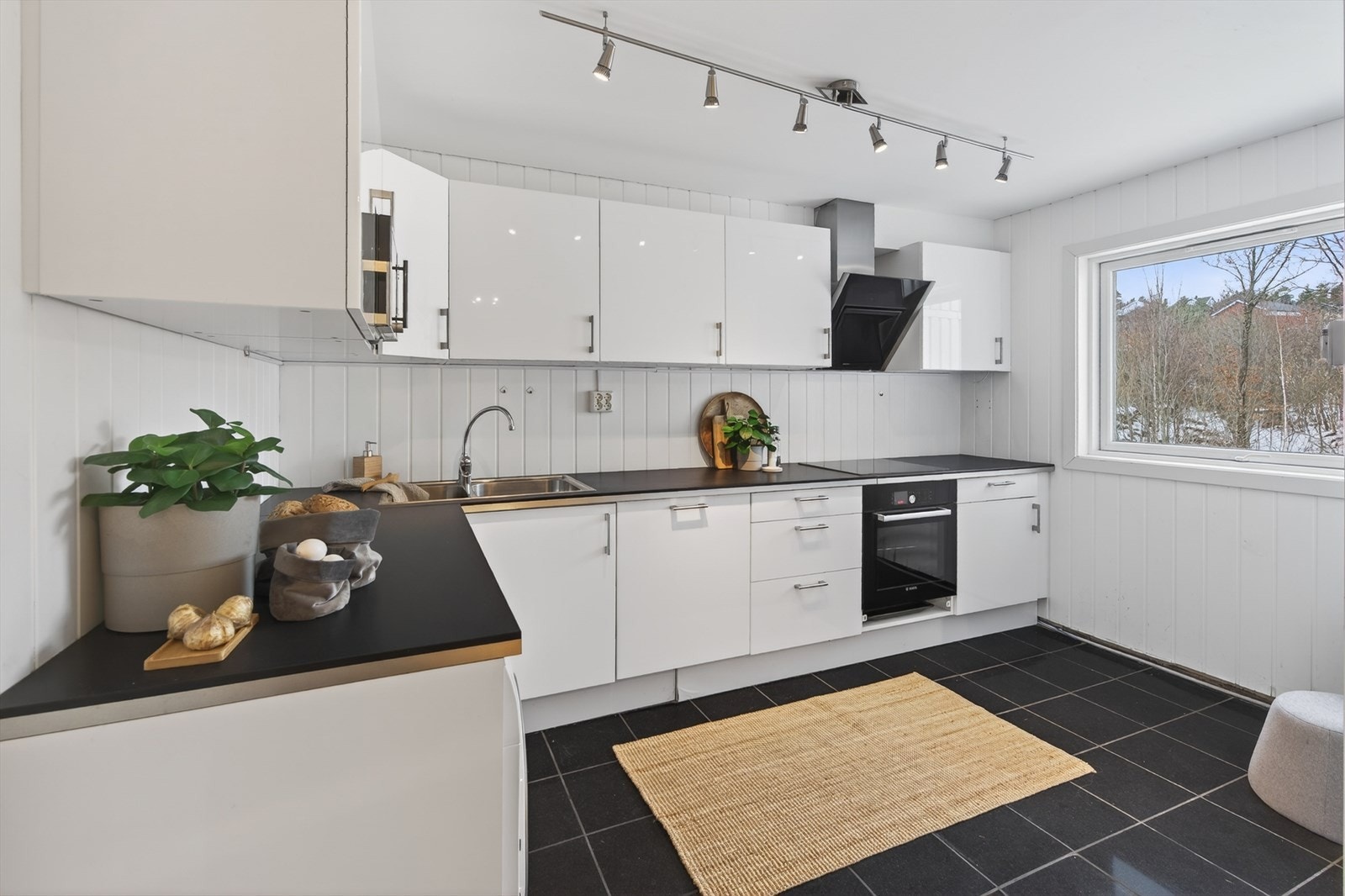 Leiligheten har kjøkkeninnredning med hvite, sletter fronter og laminert benkeplate. Galleribilde