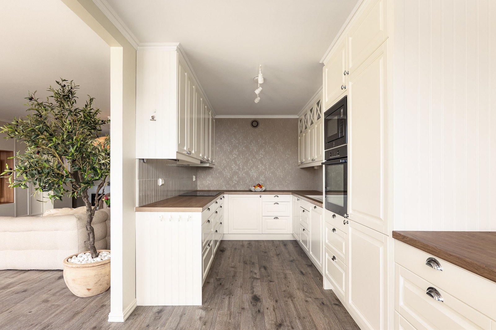 Kjøkkeninnredningen er smart utformet, arbeidssonen inntrukket og skjult fra stuens hoveddel. Dekorfliser ble i 2025 påført vegger mellom benker og overskap. Galleribilde