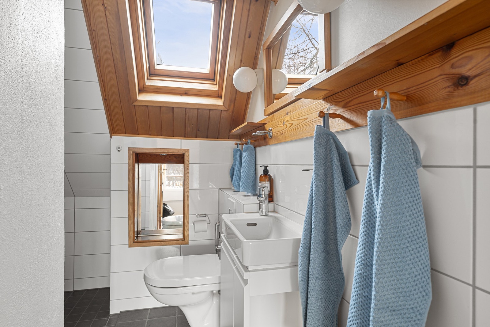 Bad i 2. etasje med takvindu som gir godt naturlig lys. Rommet er innredet med servantmøbel, vegghengt toalett og dusjløsning, og har en praktisk og arealeffektiv utforming. Galleribilde