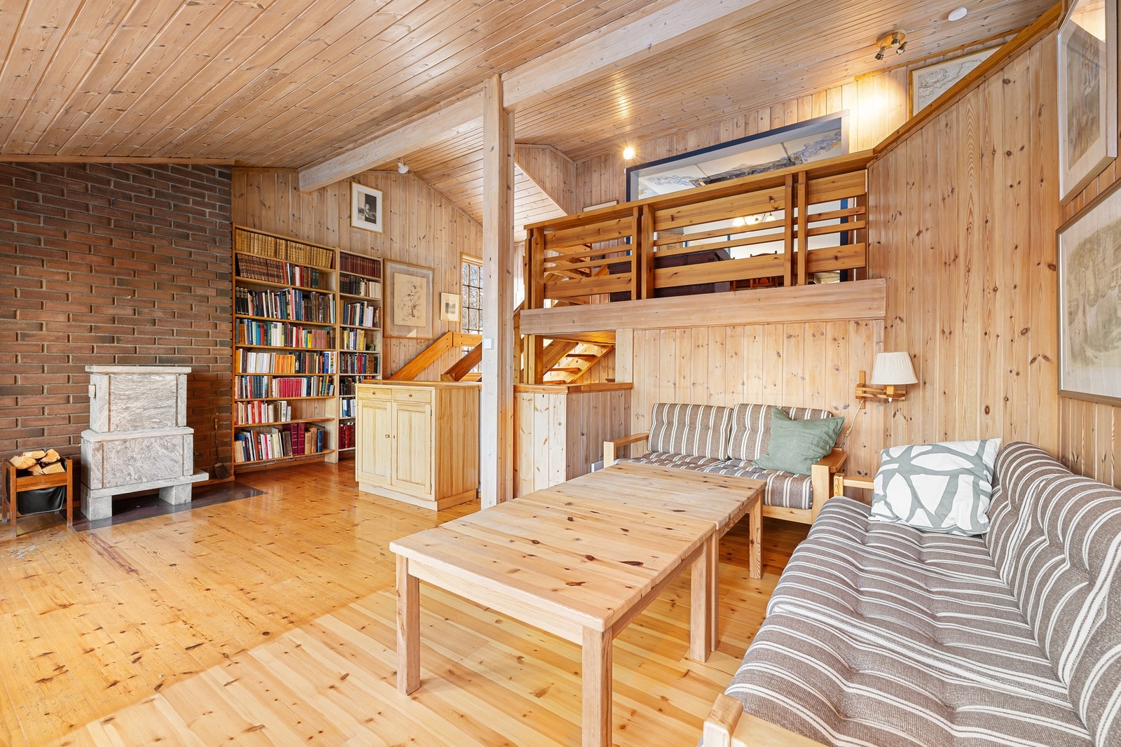 Stue med gjennomgående trepanel og særpreget halvplanløsning som skaper et sosialt oppholdsrom. Galleribilde