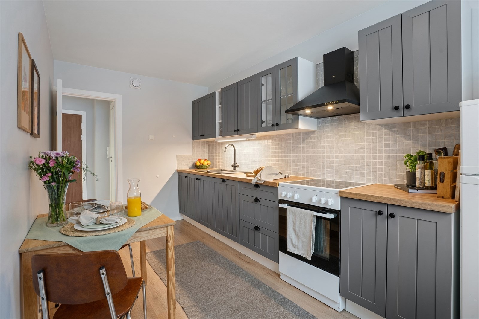 Praktisk arbeidssone med oppvaskmaskin, komfyr og ventilator. Galleribilde