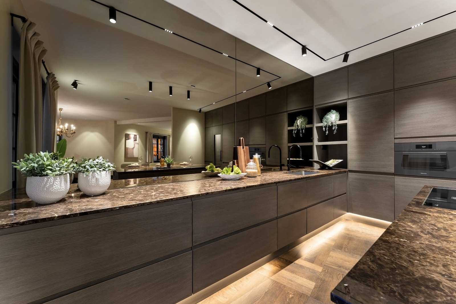 Kjøkkenet ble videre oppgradert i 2023 med utvidet kjøkkenøy, nye benkeplater og speilvegg - en løsning som både tilfører dybde og forsterker helhetsinntrykket. Galleribilde