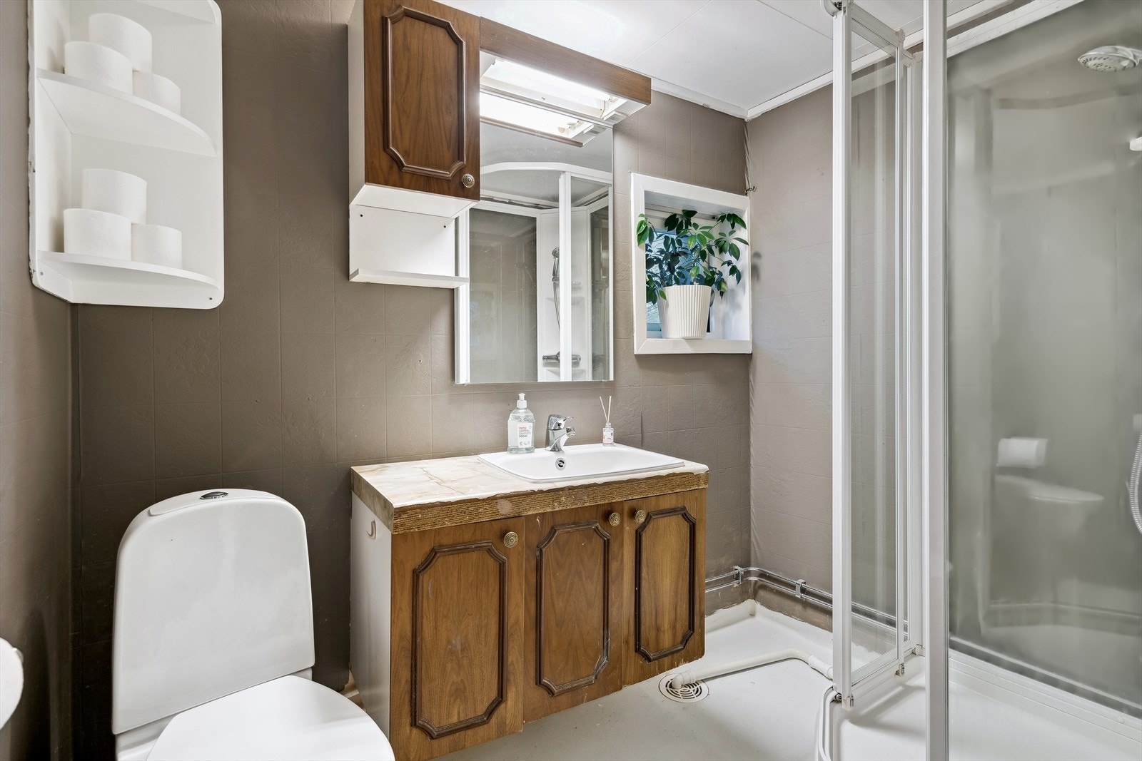 Bad med malt gulvbelegg, vinyltapet og takplater. Veggmontert toalett. Galleribilde