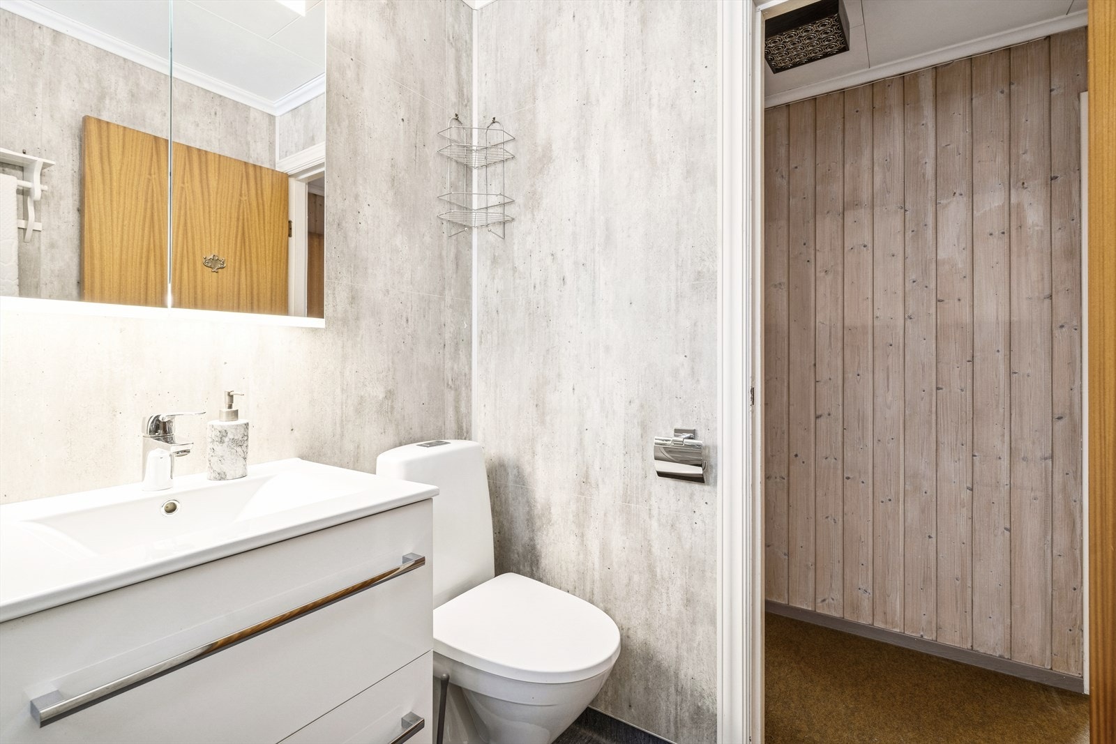 Rommet er innredet med en servantinnredning med nedfelt vask, speil, et frittstående dusjkabinett og et gulvmontert toalett. Galleribilde