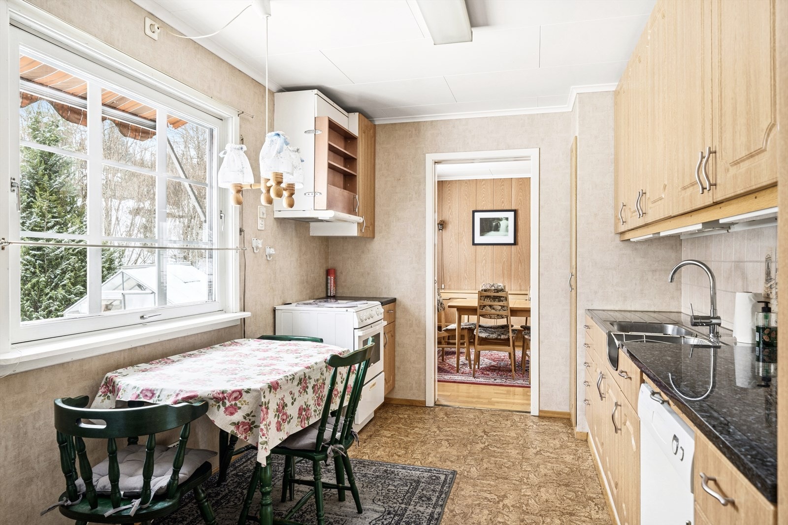 Kjøkkeninnredningen har profilerte fronter og en benkeplate i larvikitt Veggpartiet mellom benkeplaten og overskapene er flislagt, og innredningen er utstyrt med benkebeslag og vask i rustfritt stål. Galleribilde